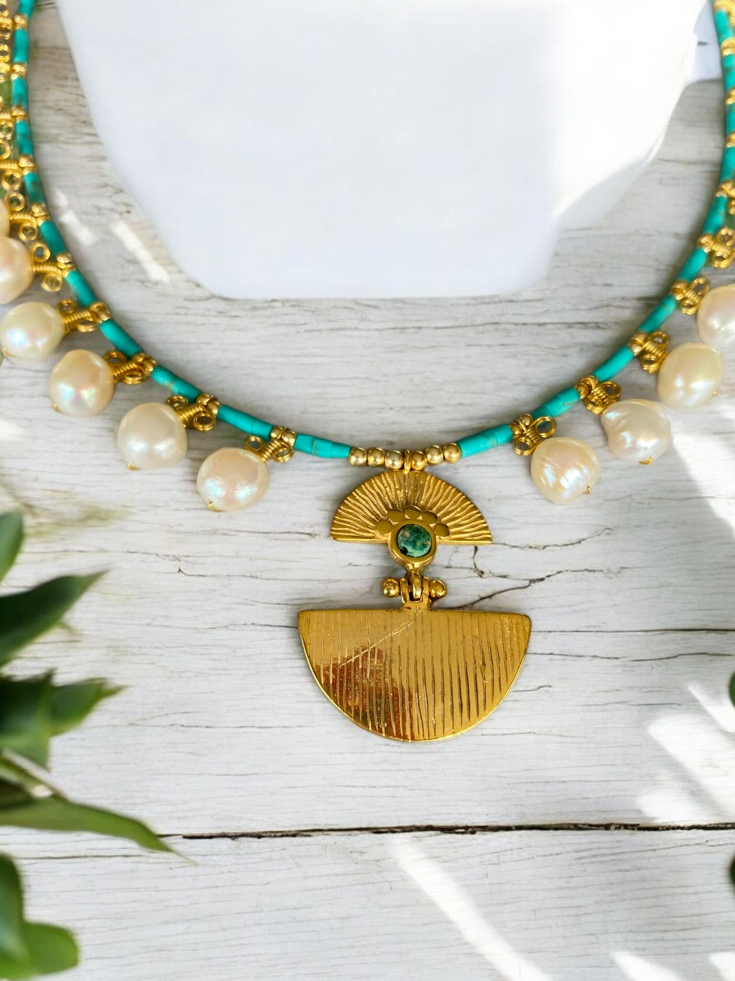 Ariadne Necklace with Pearl and Turquoise Gemstone in Sterling Silver 14K Gold Plated placed on a light wooden background.