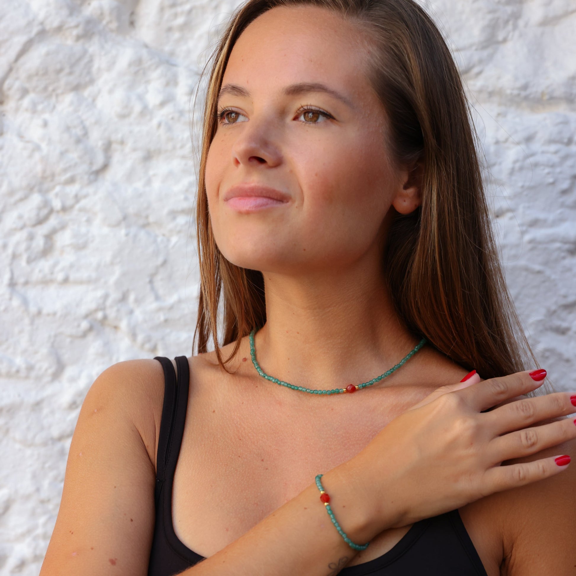 Aventurine and Carnelian gemstone necklace worn by a woman against a white textured background.