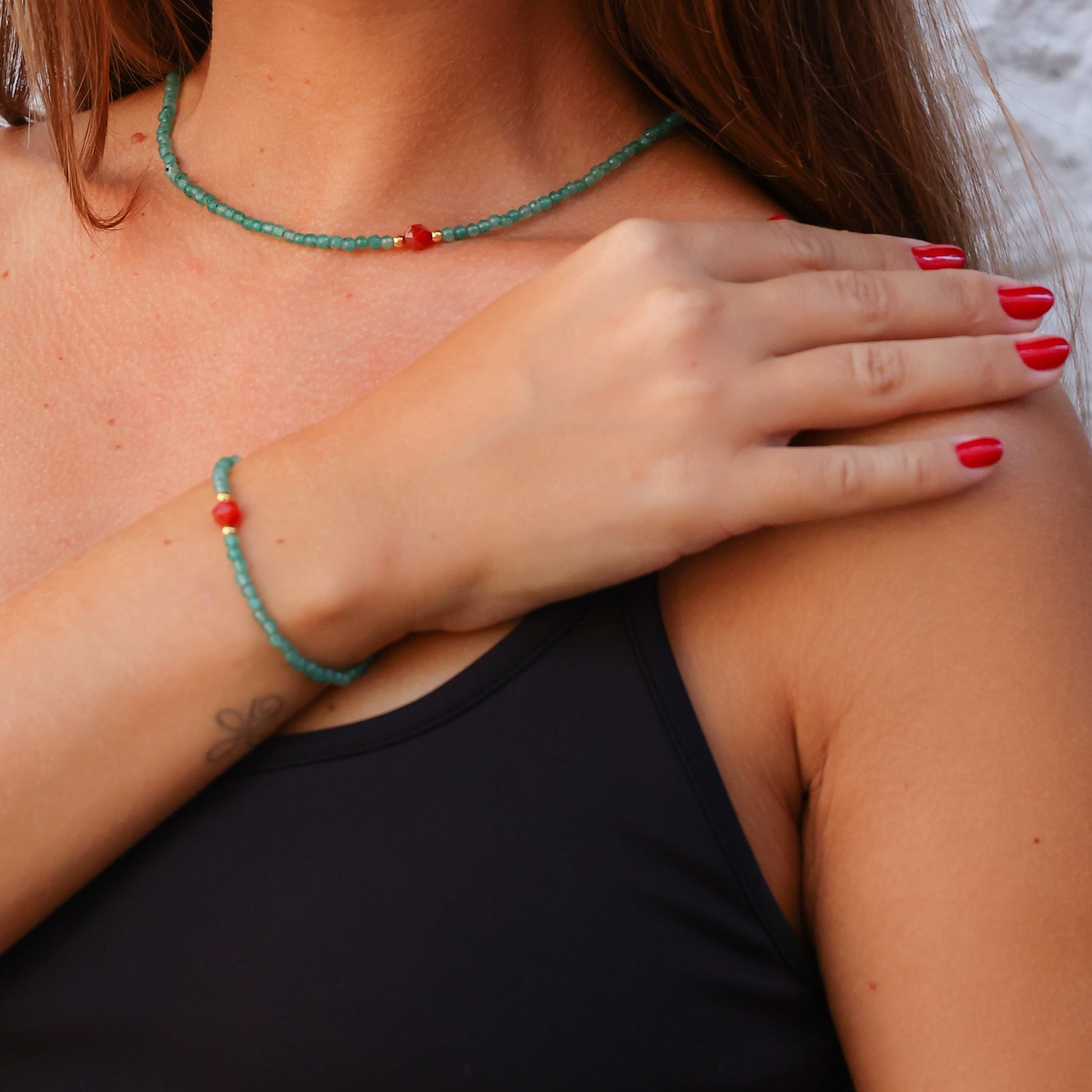 Close-up of a woman wearing a delicate Aventurin and Carnelian gemstone necklace and bracelet