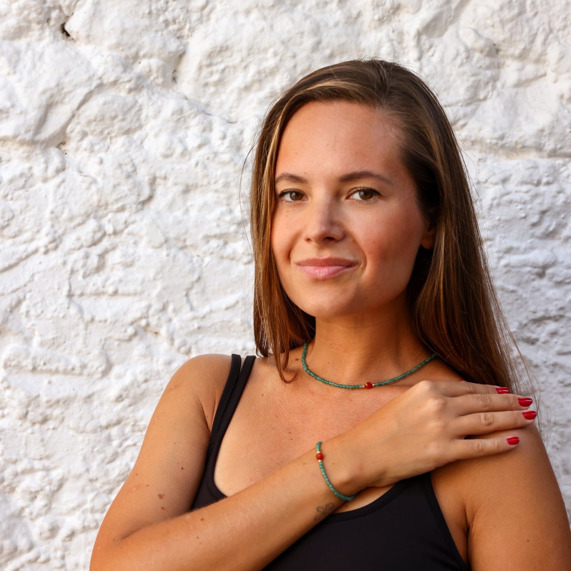 Woman wearing Aventurine & Carnelian Gemstone Necklace against white stone background