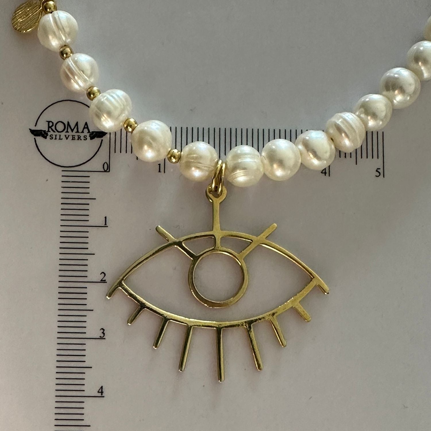 Baroque Pearl Silver Eye Necklace with gold eye pendant and ruler for scale.