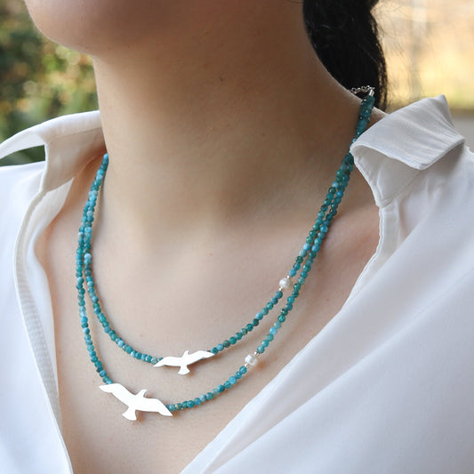 Close-up of Big and Small Seagull Apatite Silver Necklace on woman's neck wearing a white shirt.