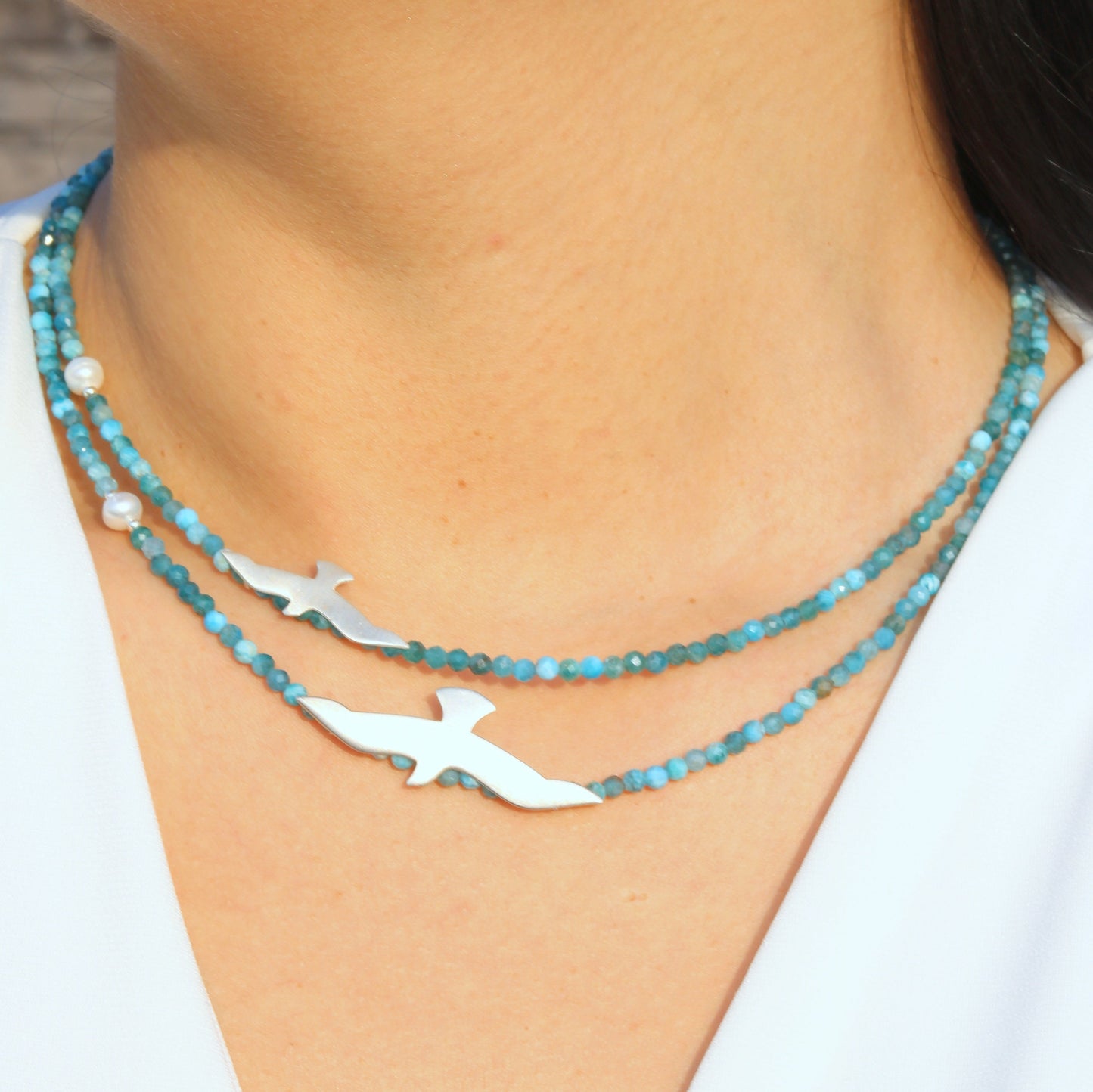 Close-up of Big and Small Seagull Apatite Silver Necklace on woman's neck.