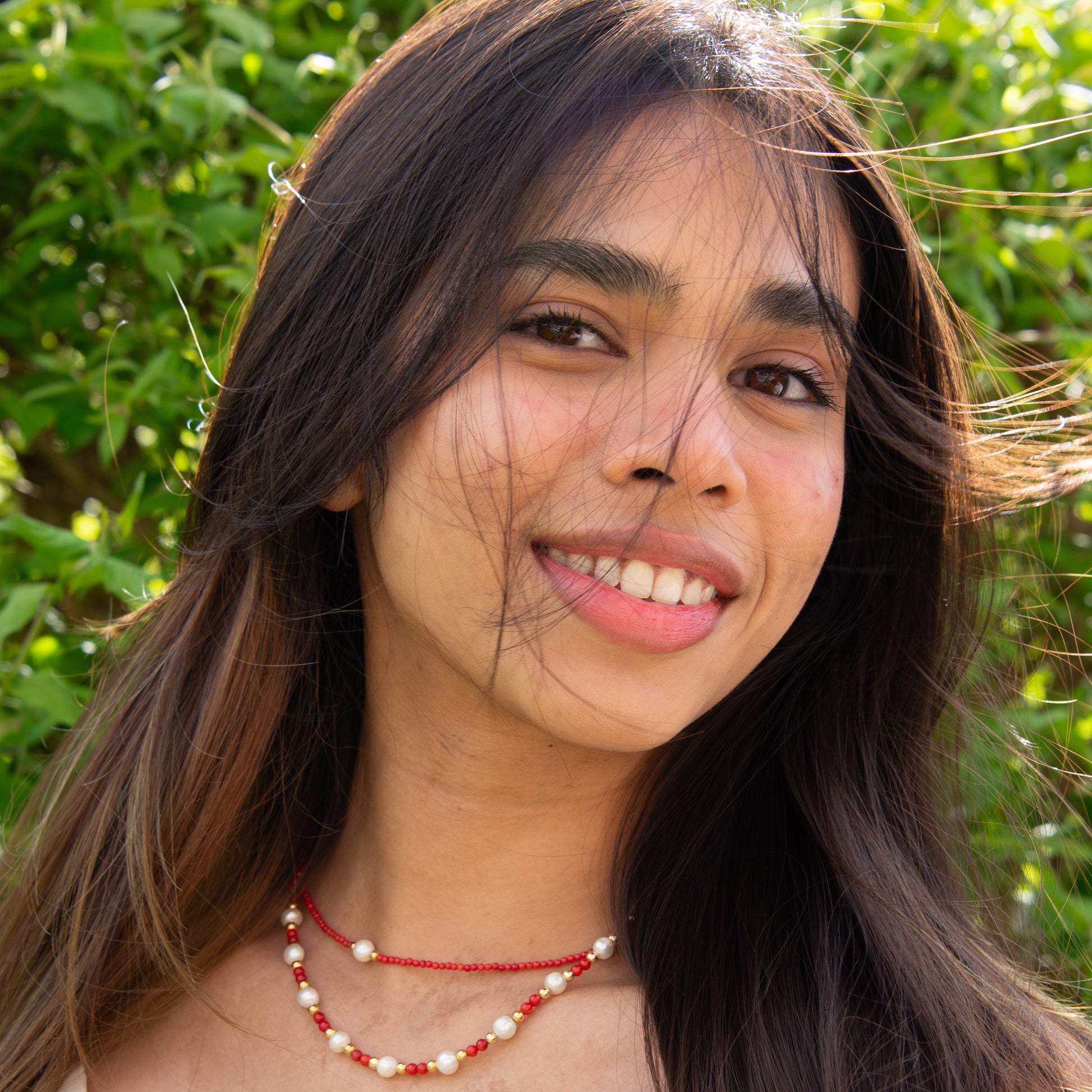 Woman wearing Cueno Coral Gemstone Freshwater Pearl Necklace with a natural background