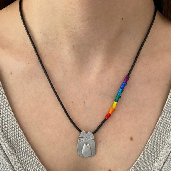 Close-up of a Cutie Cat Silver Necklace with a rainbow thread accent worn by a person.