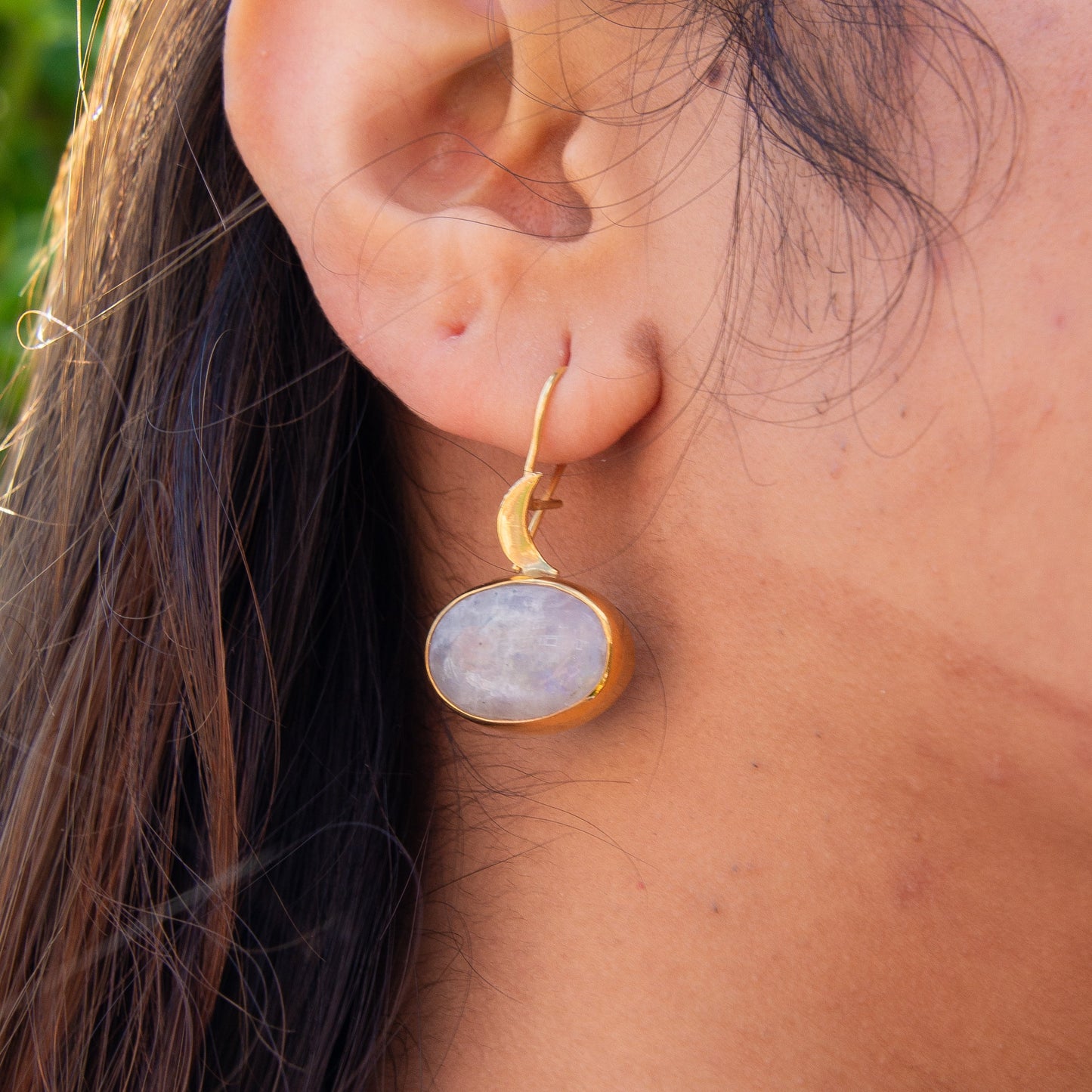 Close-up of woman wearing Day Moonstone Silver Earrings with gold crescent moon and round moonstone gem