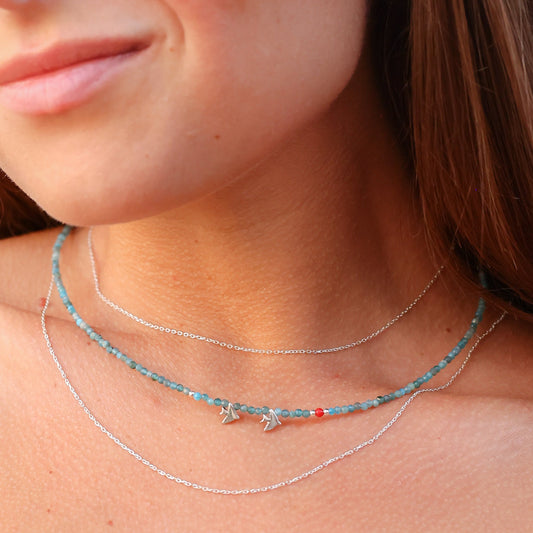 Close-up shot of a woman wearing the Duo Birdie Minimal Silver Necklace, featuring a delicate silver chain and small bird charms.