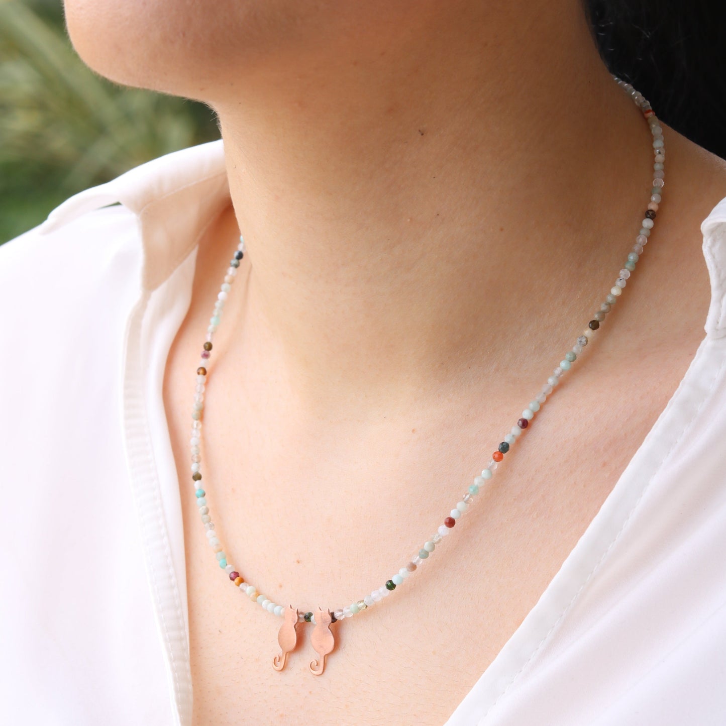 Close-up of Duo Mini Cats Silver Necklace worn by a woman in a white blouse