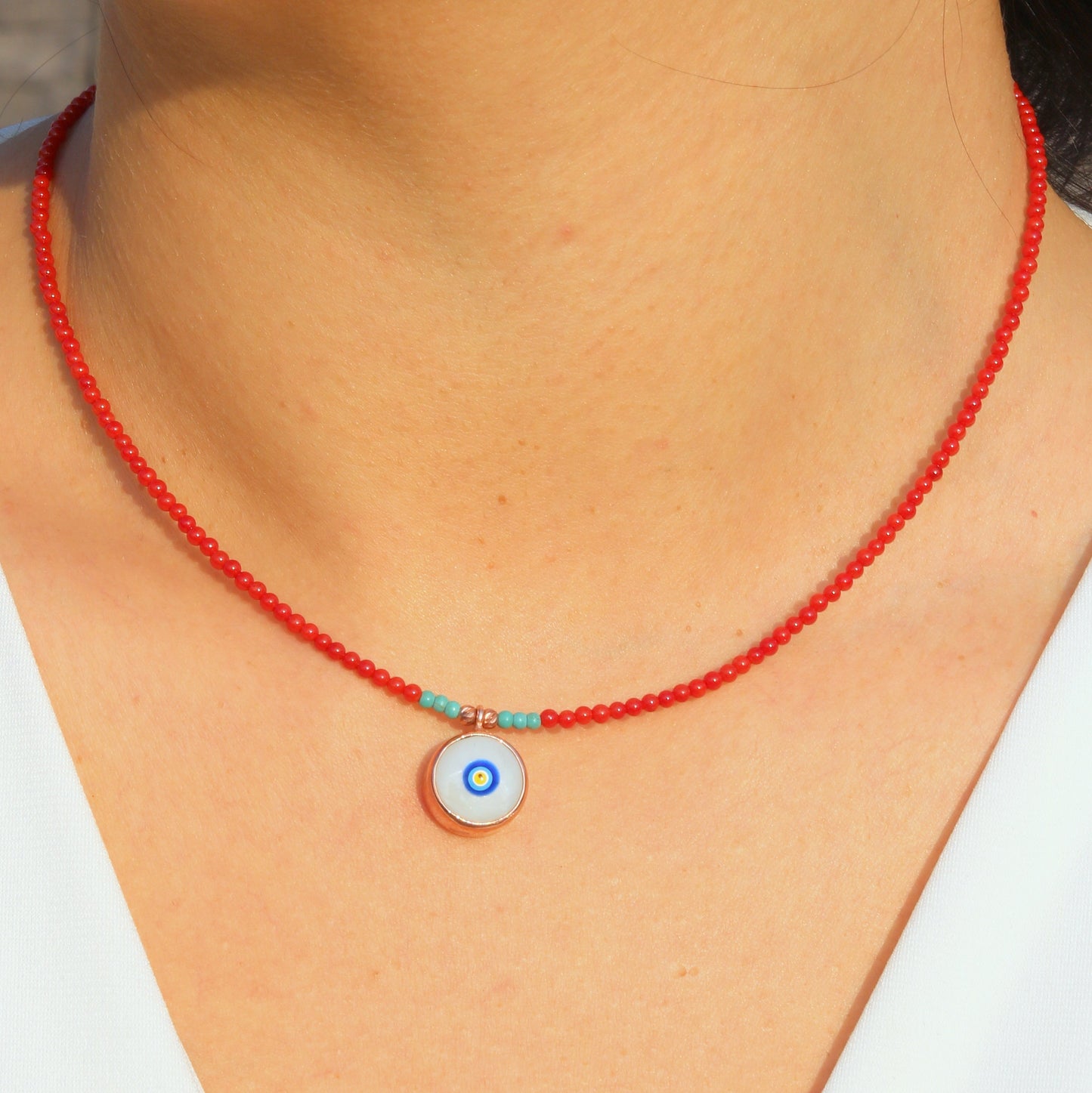 Evil Eye Coral Gemstone Necklace with red beads and turquoise accents displayed on a woman's neck.