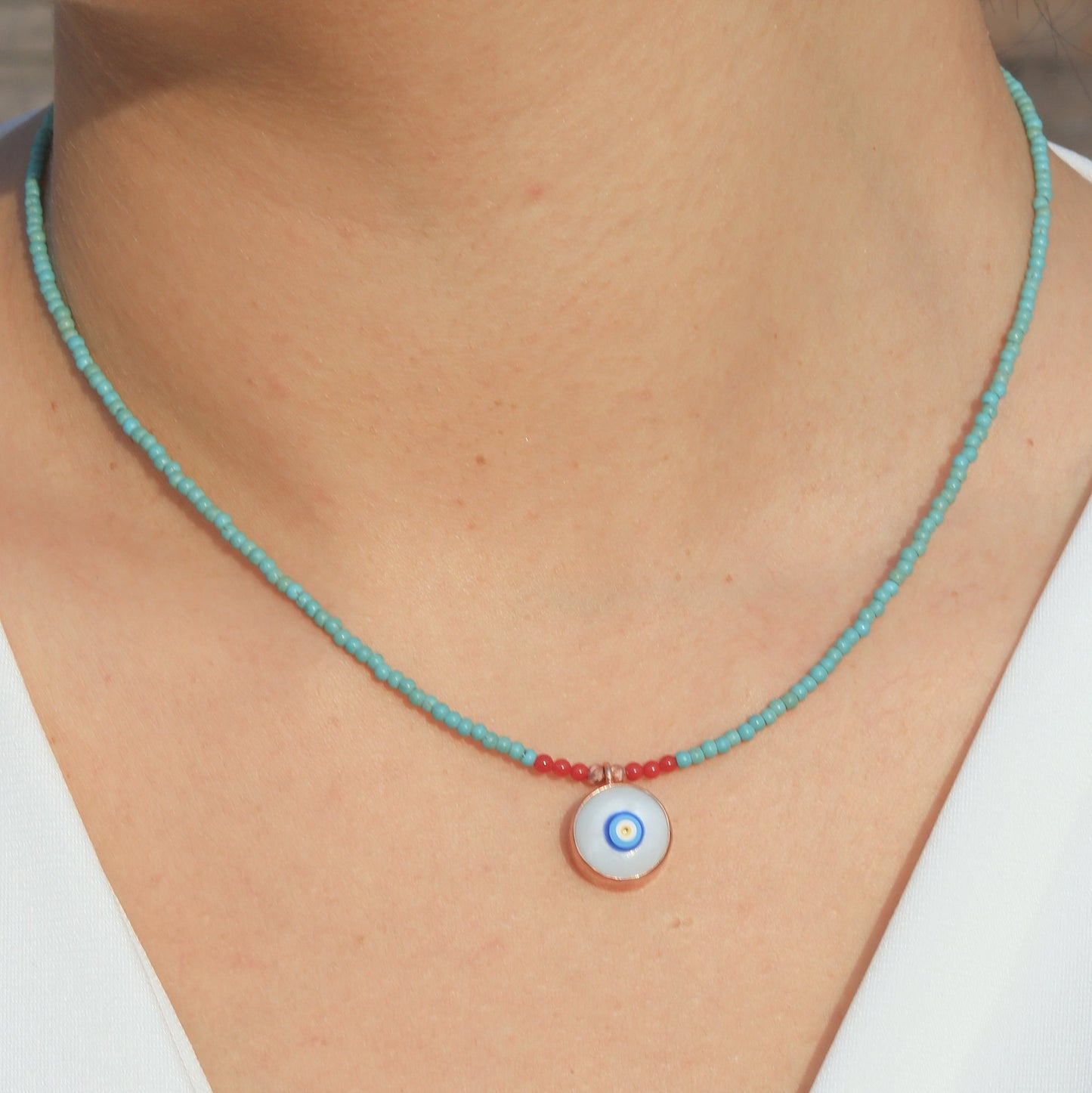 Evil Eye Howlite Beaded Necklace on a person’s neck, featuring turquoise beads and a central blue and white evil eye pendant.