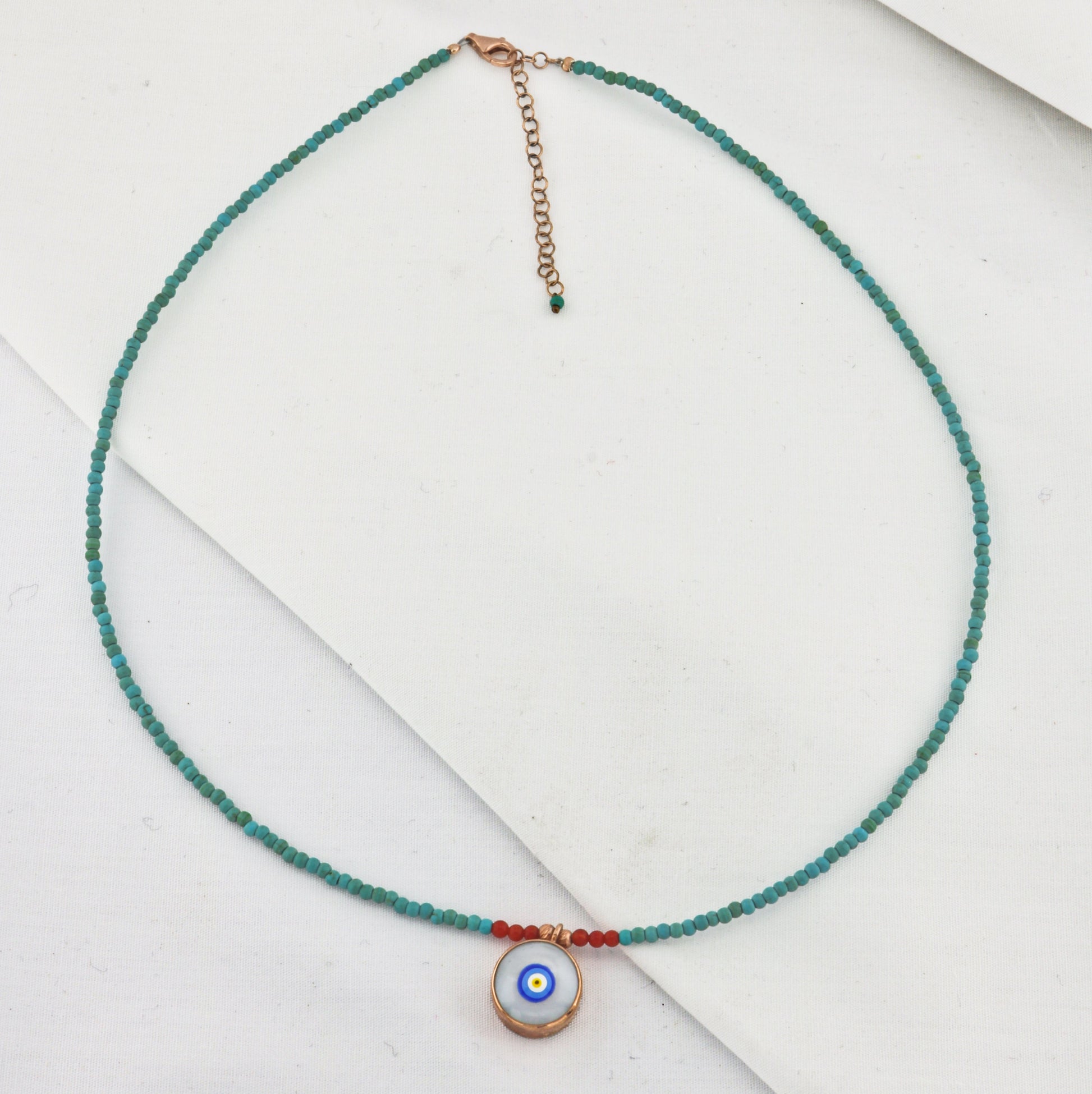 Evil Eye Howlite Beaded Necklace with turquoise and red beads, featuring a central Evil Eye pendant, set on a white background.