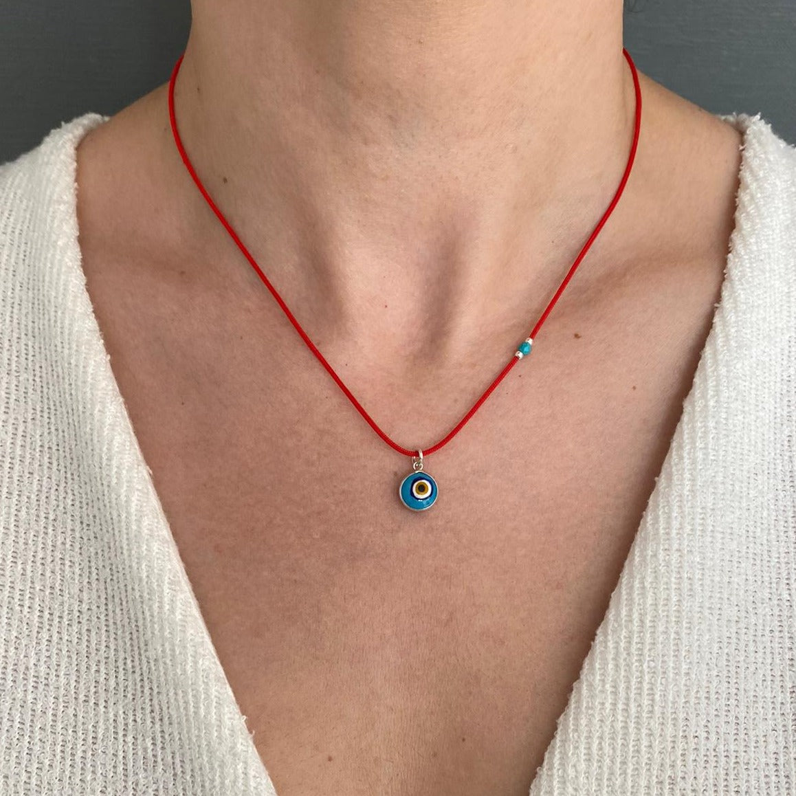 Evil Eye Red Cord Necklace with blue evil eye pendant worn on a person.