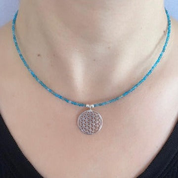 Close-up of Flower of Life Apatite Necklace with a blue beaded chain and a silver pendant featuring intricate sacred geometry design.