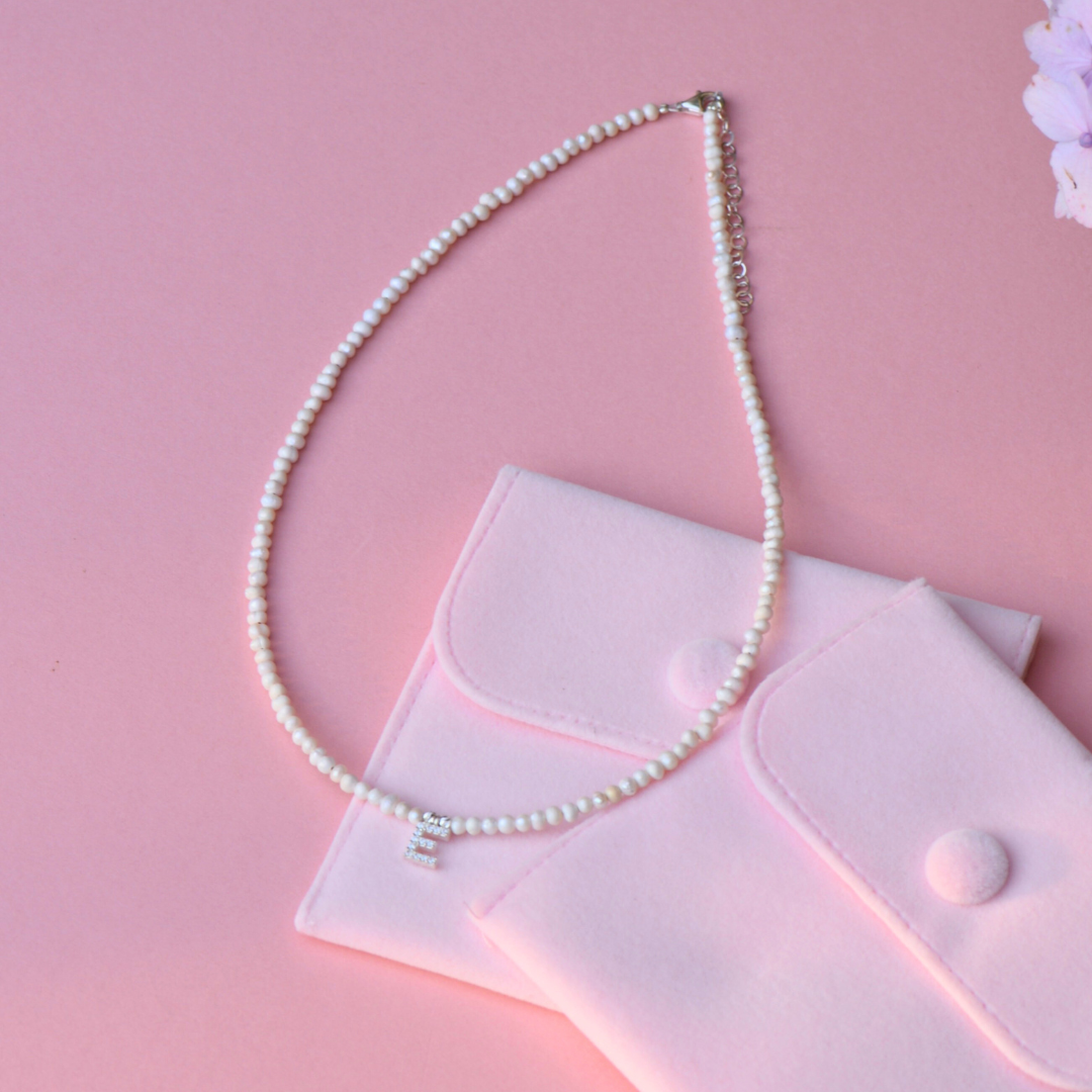 Freshwater Pearls Initial Necklace on pink background with pouches