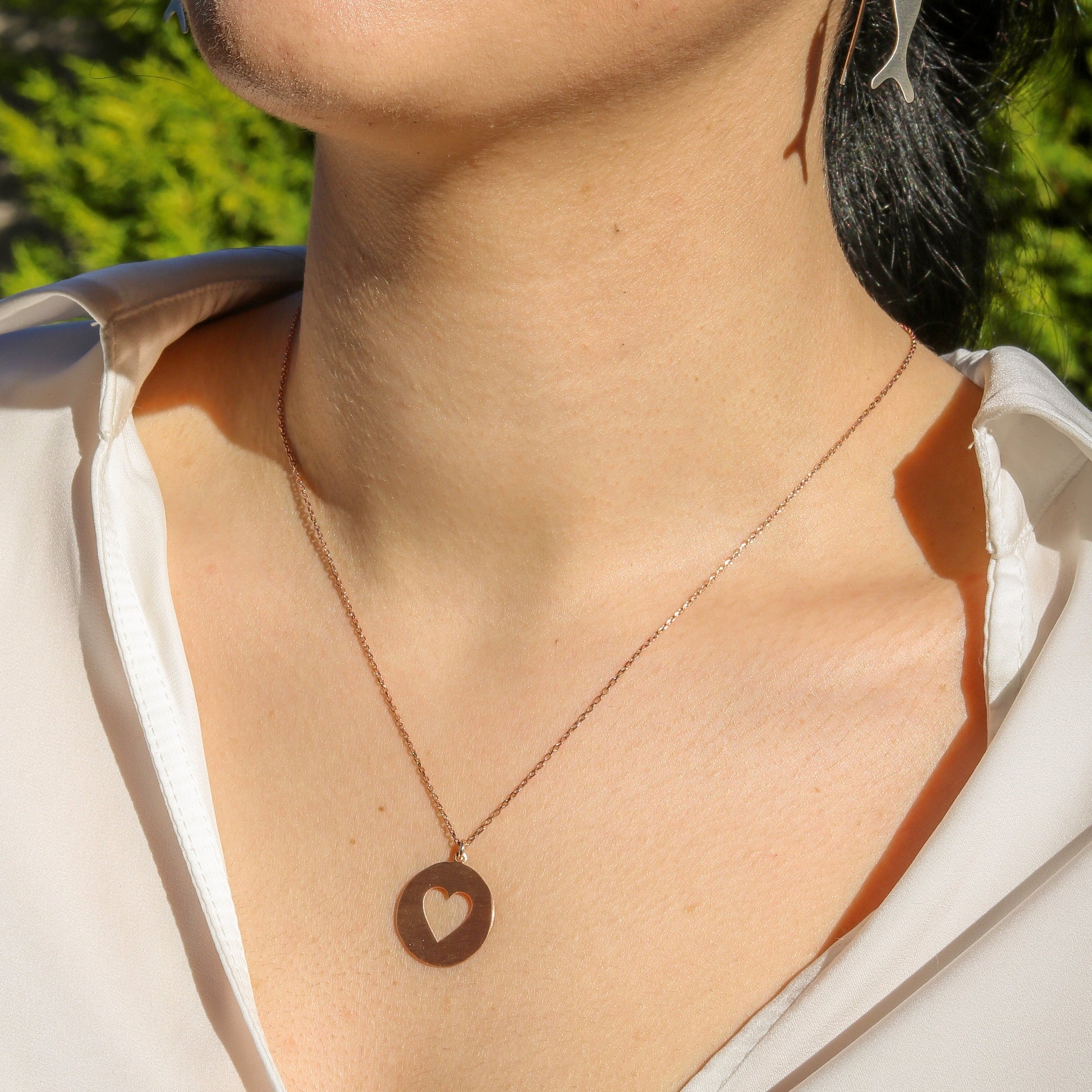 Woman wearing a Heart in Silver Disc Necklace paired with a white blouse.