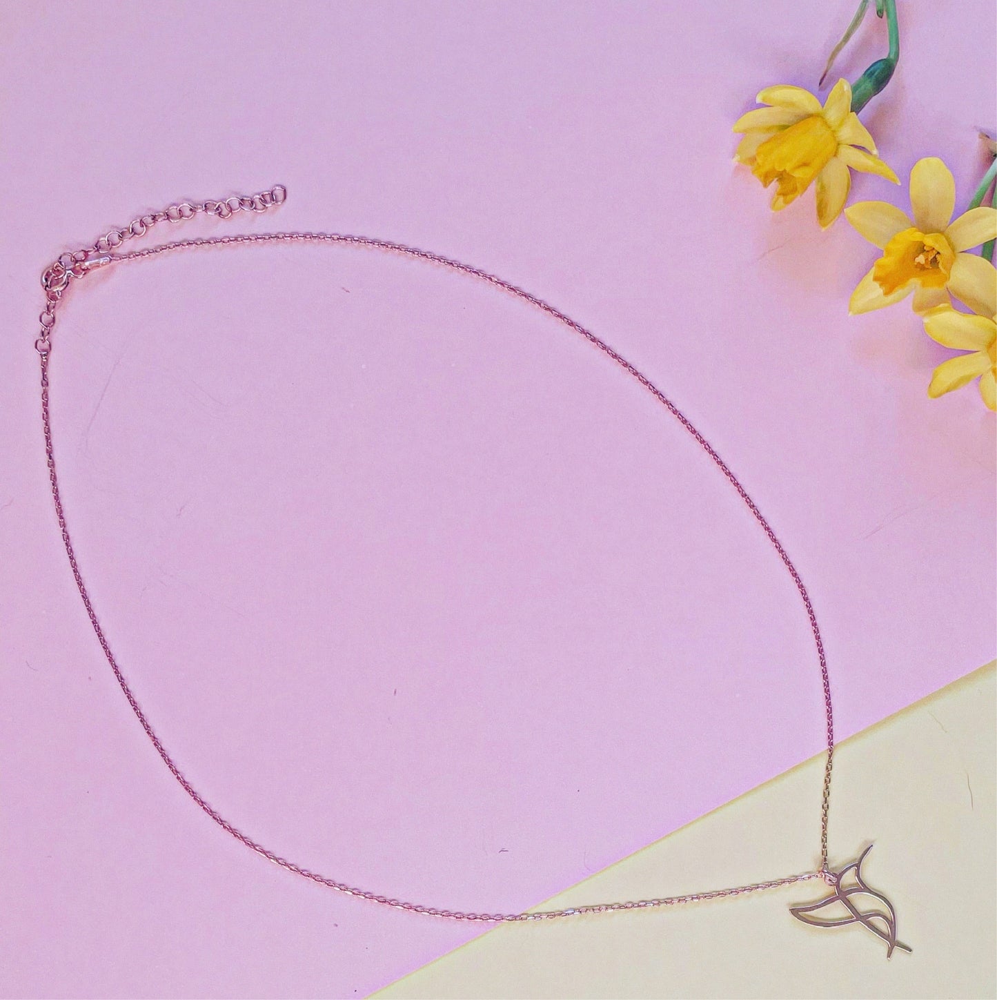 Hummingbird Sterling Silver Necklace on Pink Background with Yellow Flowers