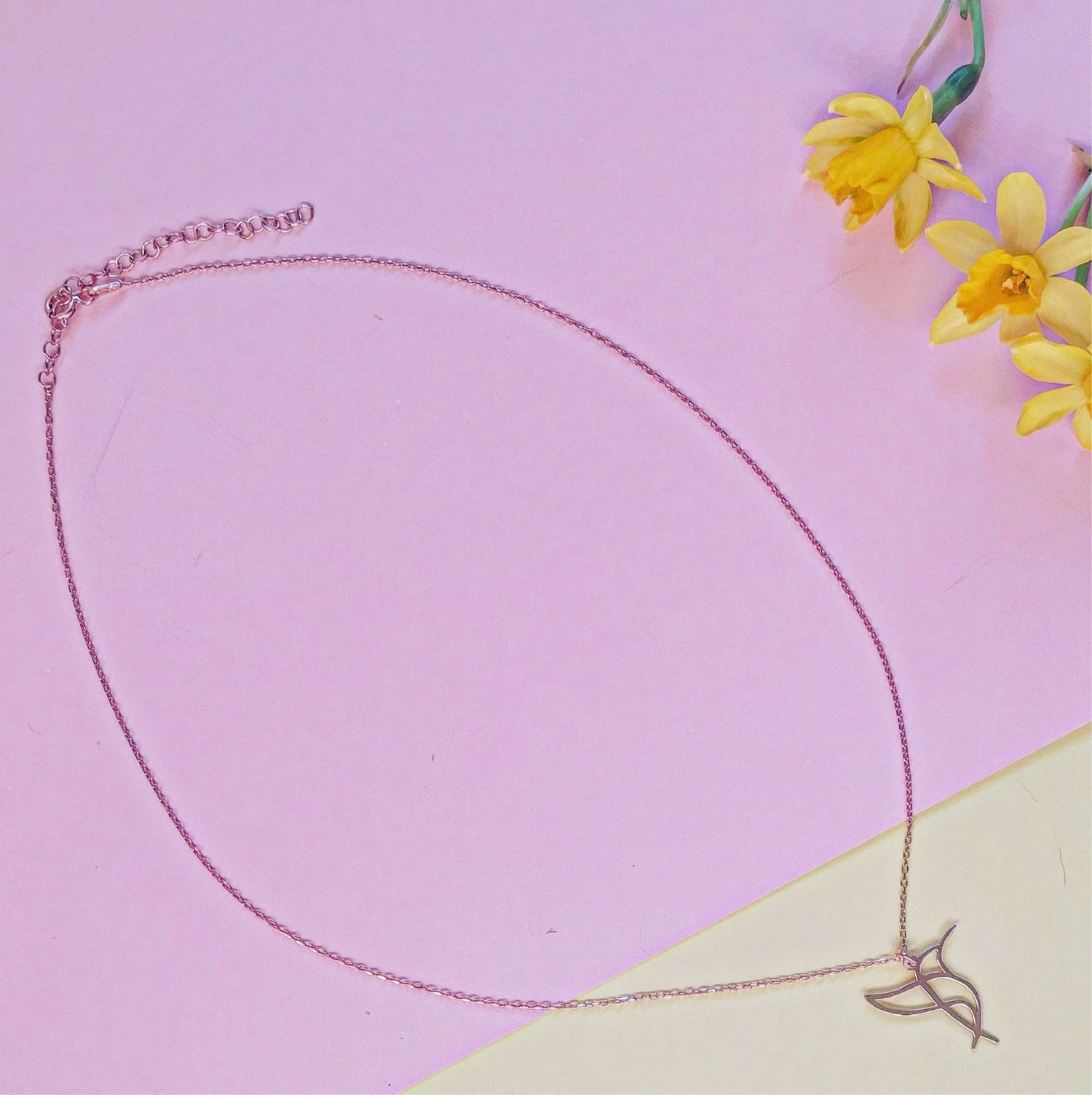 Hummingbird Sterling Silver Necklace on Pink Background with Yellow Flowers