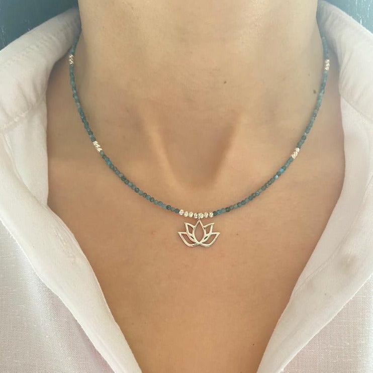 Woman wearing a Lotus Flower Apatite Necklace with delicate blue beads and a silver lotus pendant.