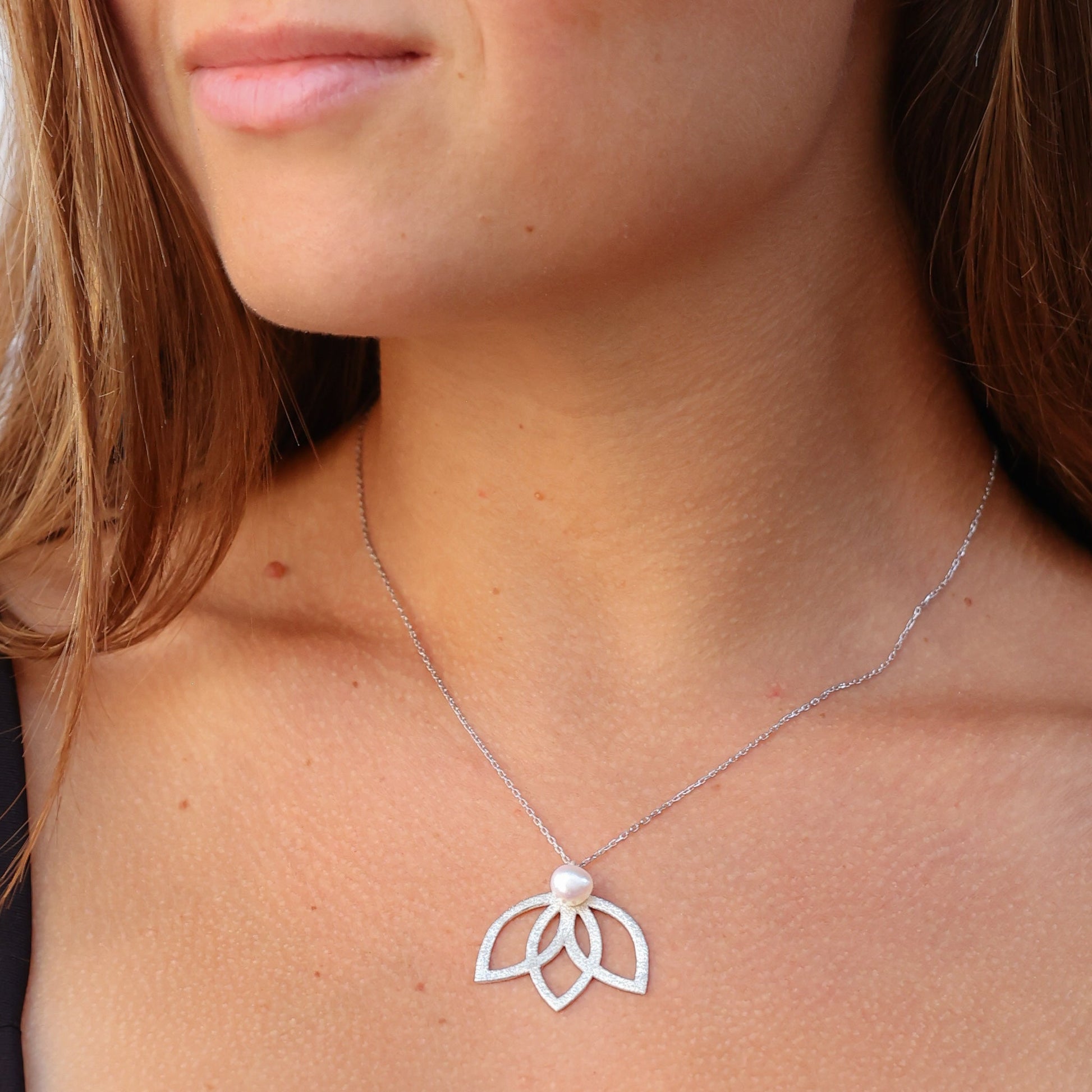 Close-up of woman wearing Lotus Flower Silver and Pearl Necklace.