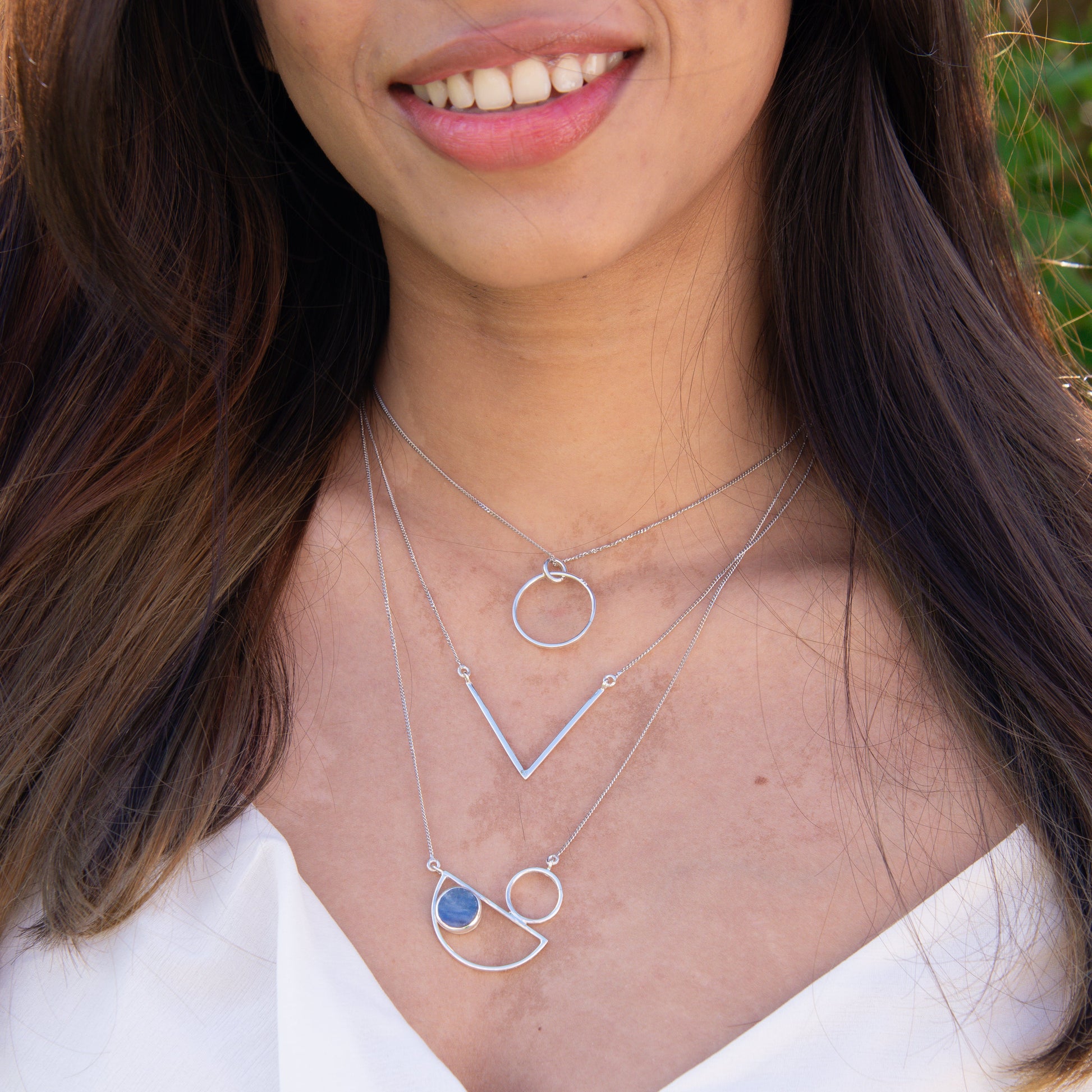 Messina Layered Silver Necklace Set featuring three distinct geometric pendants on a woman's neck