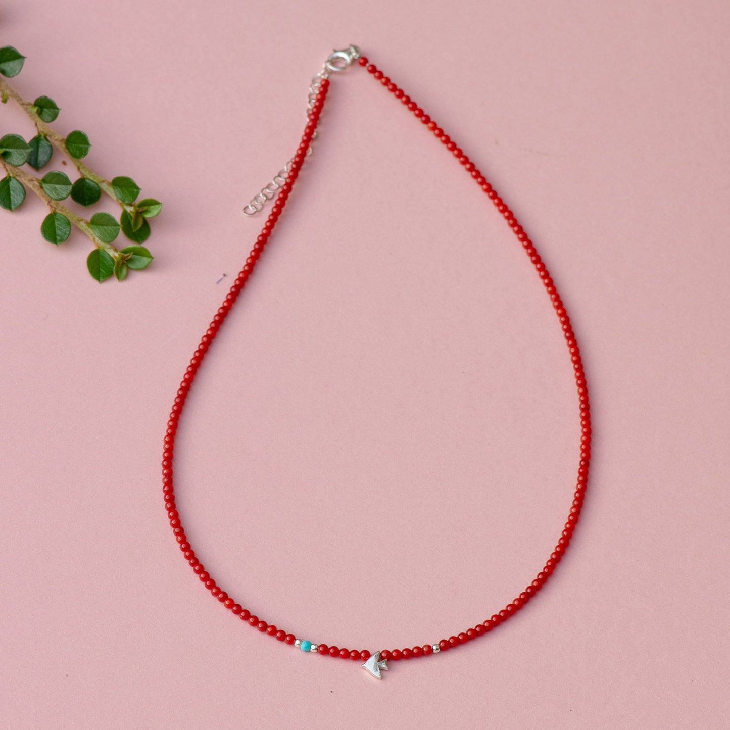 Minimal Birdie Silver and Coral Gemstone Necklace with delicate beads on a pink background