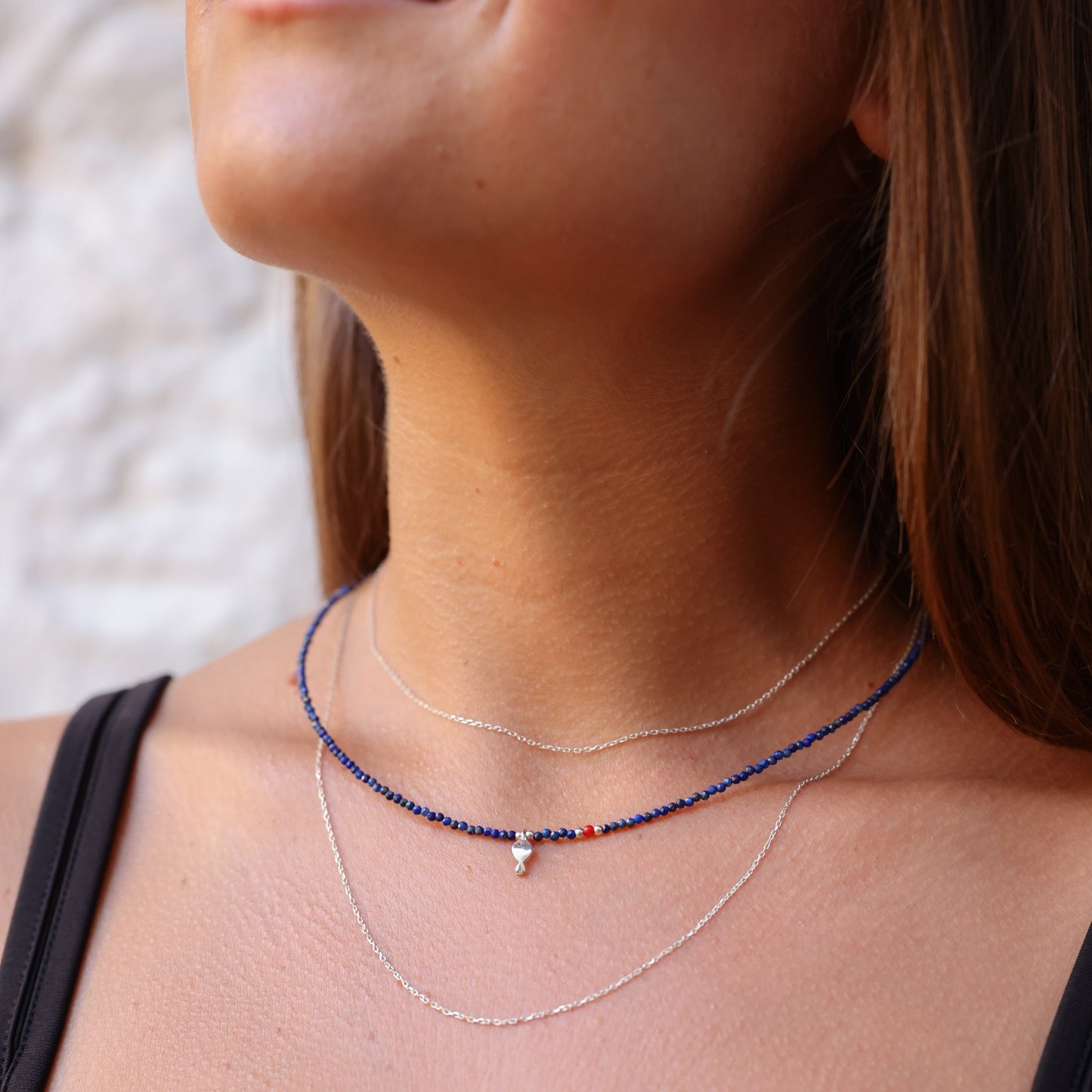 Minimal Lapis Lazuli Gemstone Silver Fish Necklace showcased on a woman's neck.