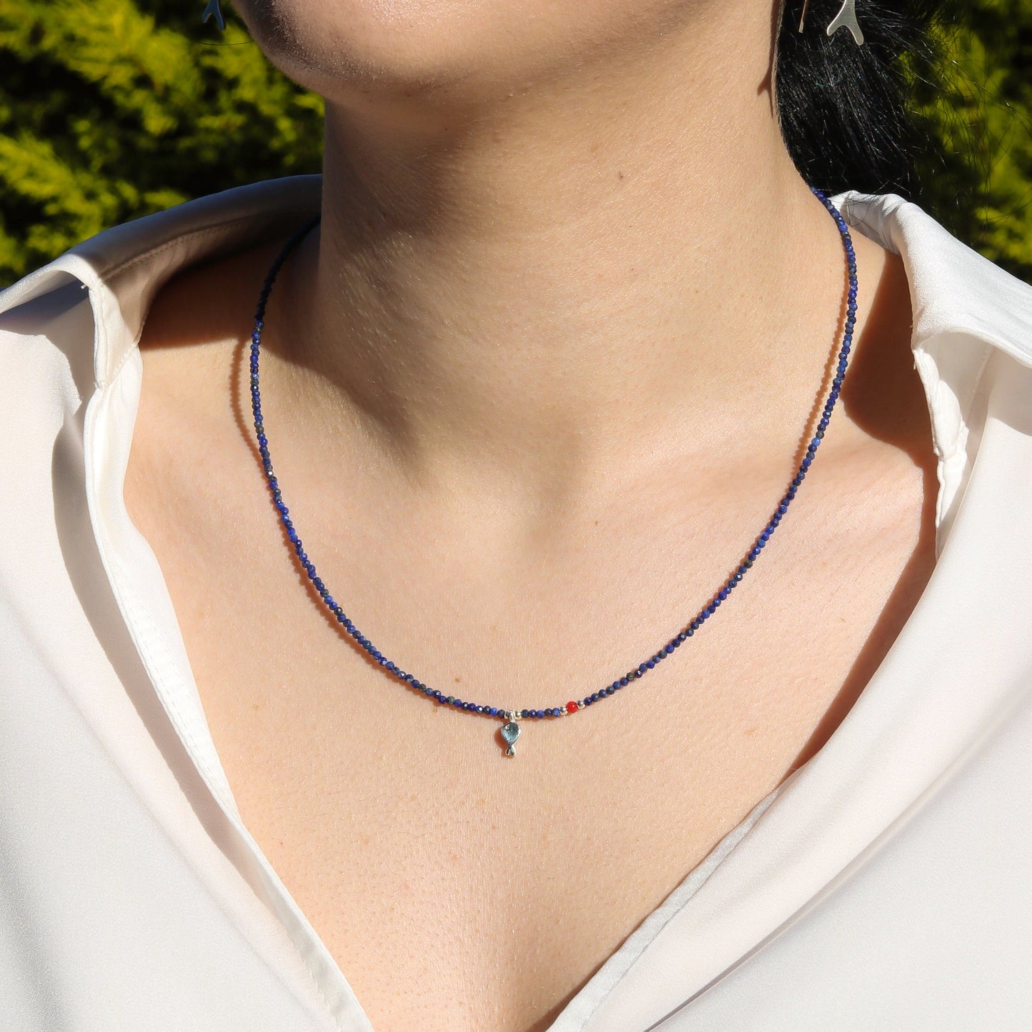 Minimal Lapis Lazuli Gemstone Silver Fish Necklace worn by a woman in a white shirt.