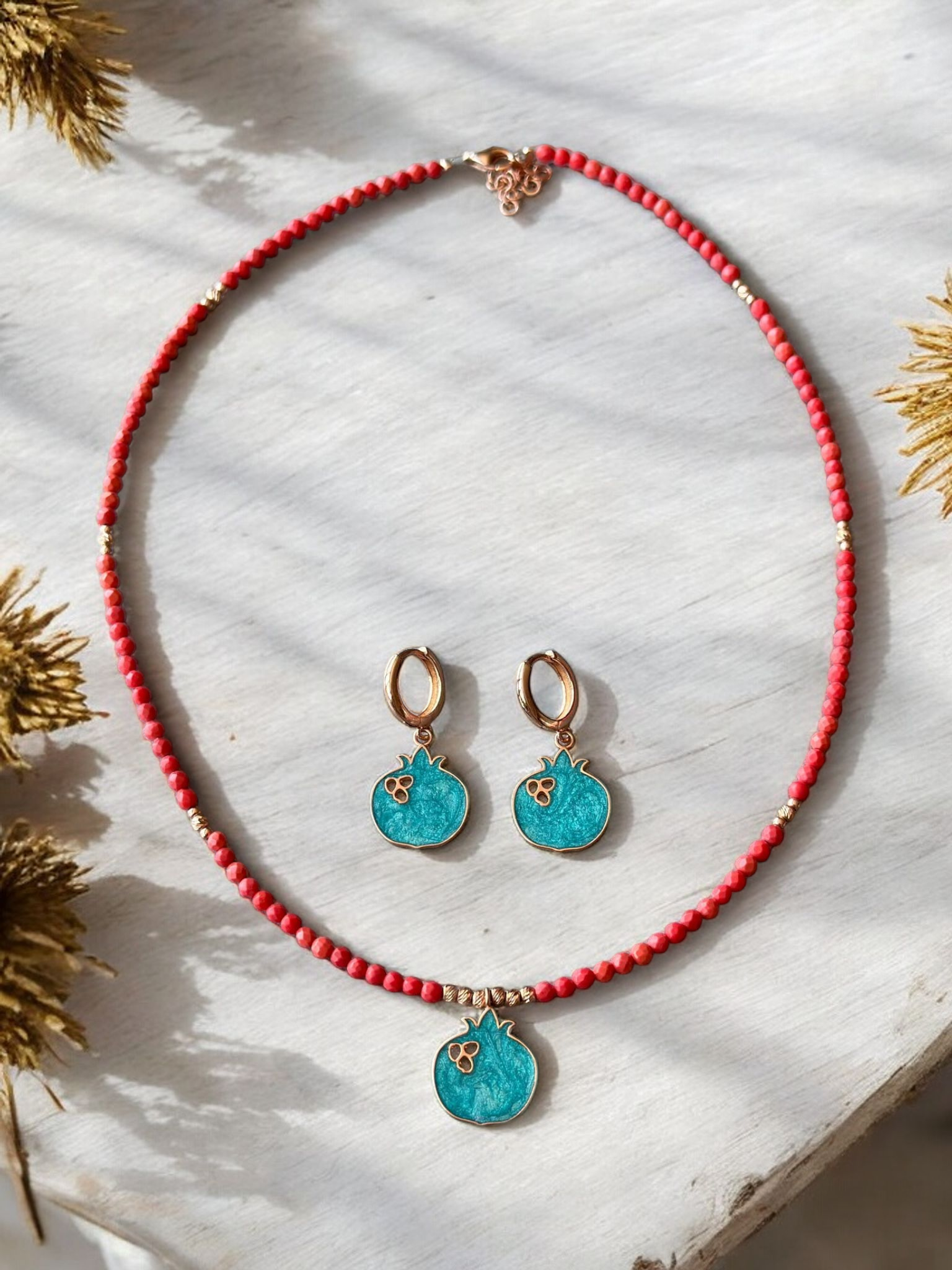 Nar Red Coral Gemstone Necklace and Earrings Set with turquoise pomegranate pendants on a light wooden background.