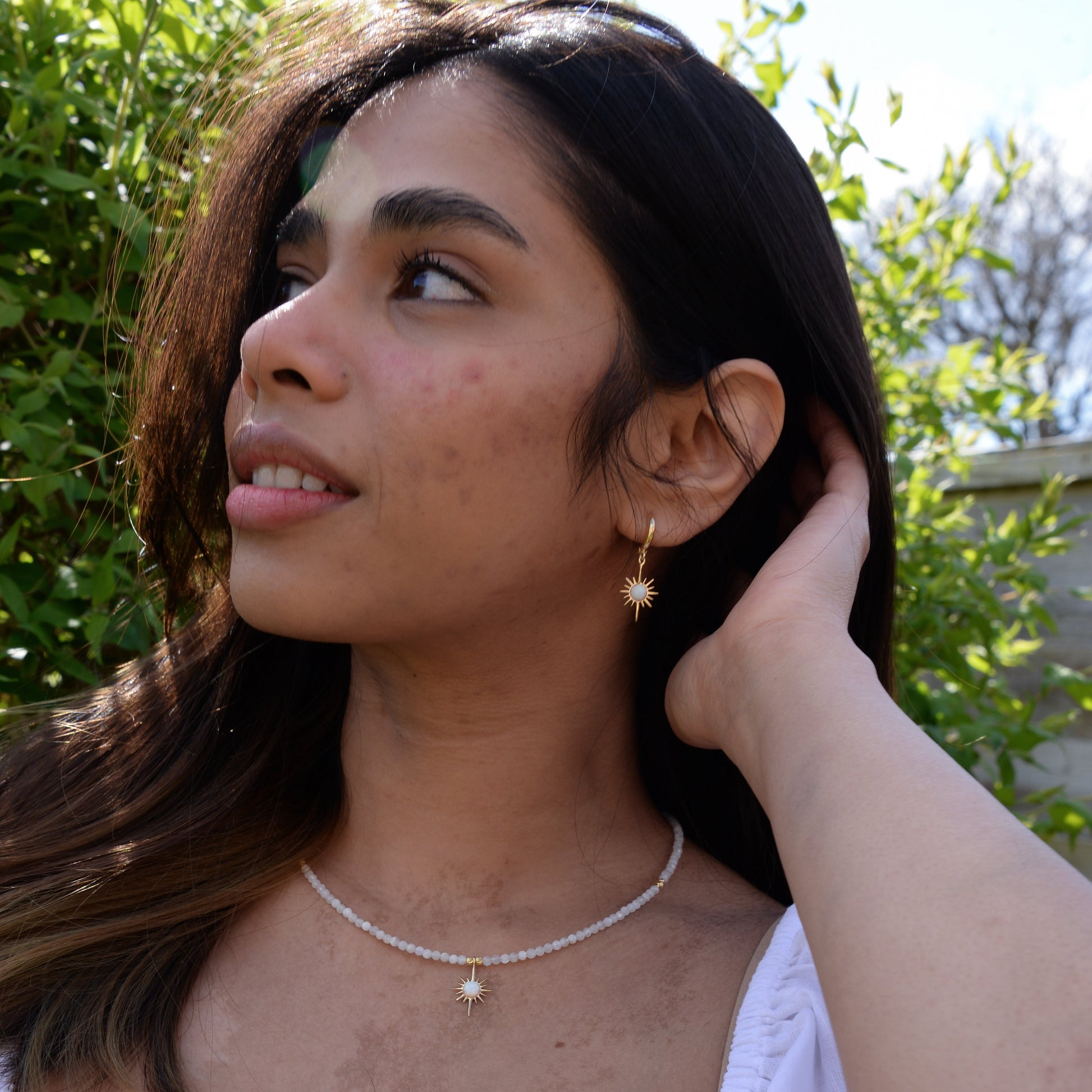 Woman wearing North Star Moonstone Dangle Drop Earrings and matching necklace in a natural outdoor setting