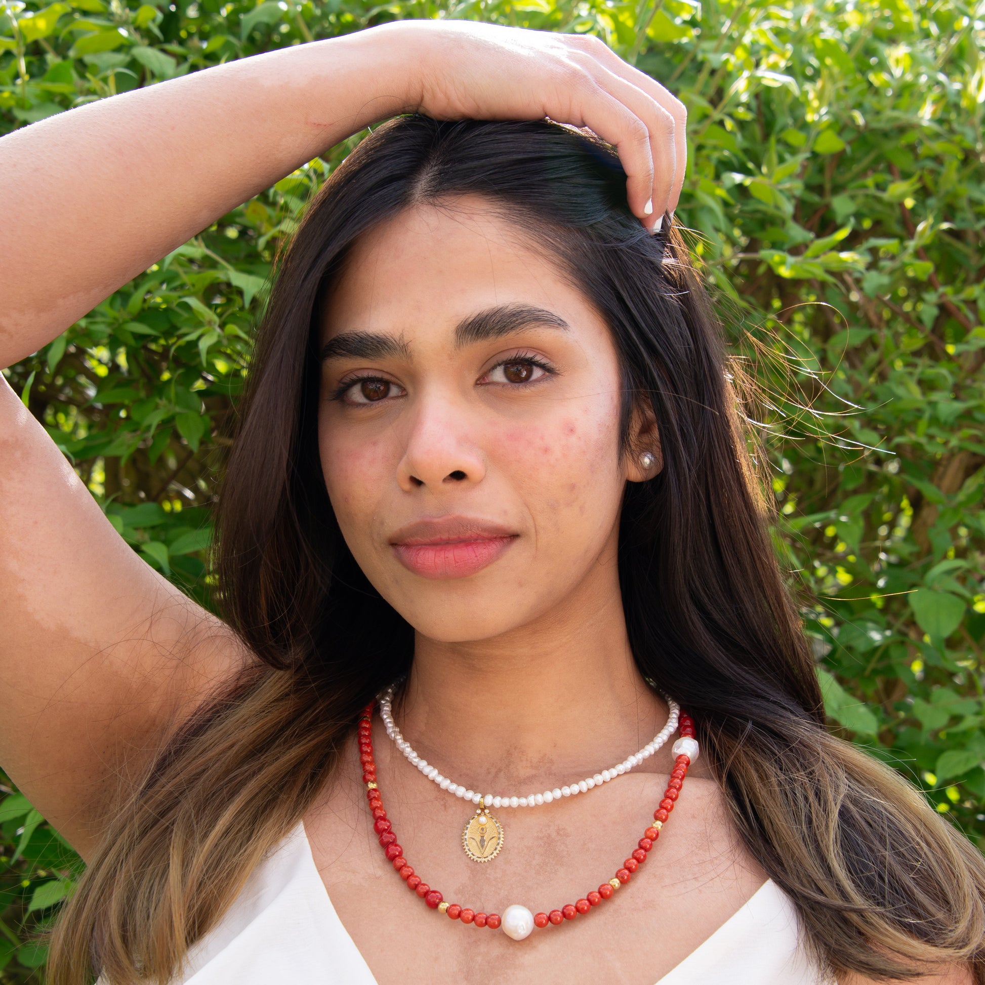 Woman wearing a pearl necklace with a rebirth symbol plate pendant