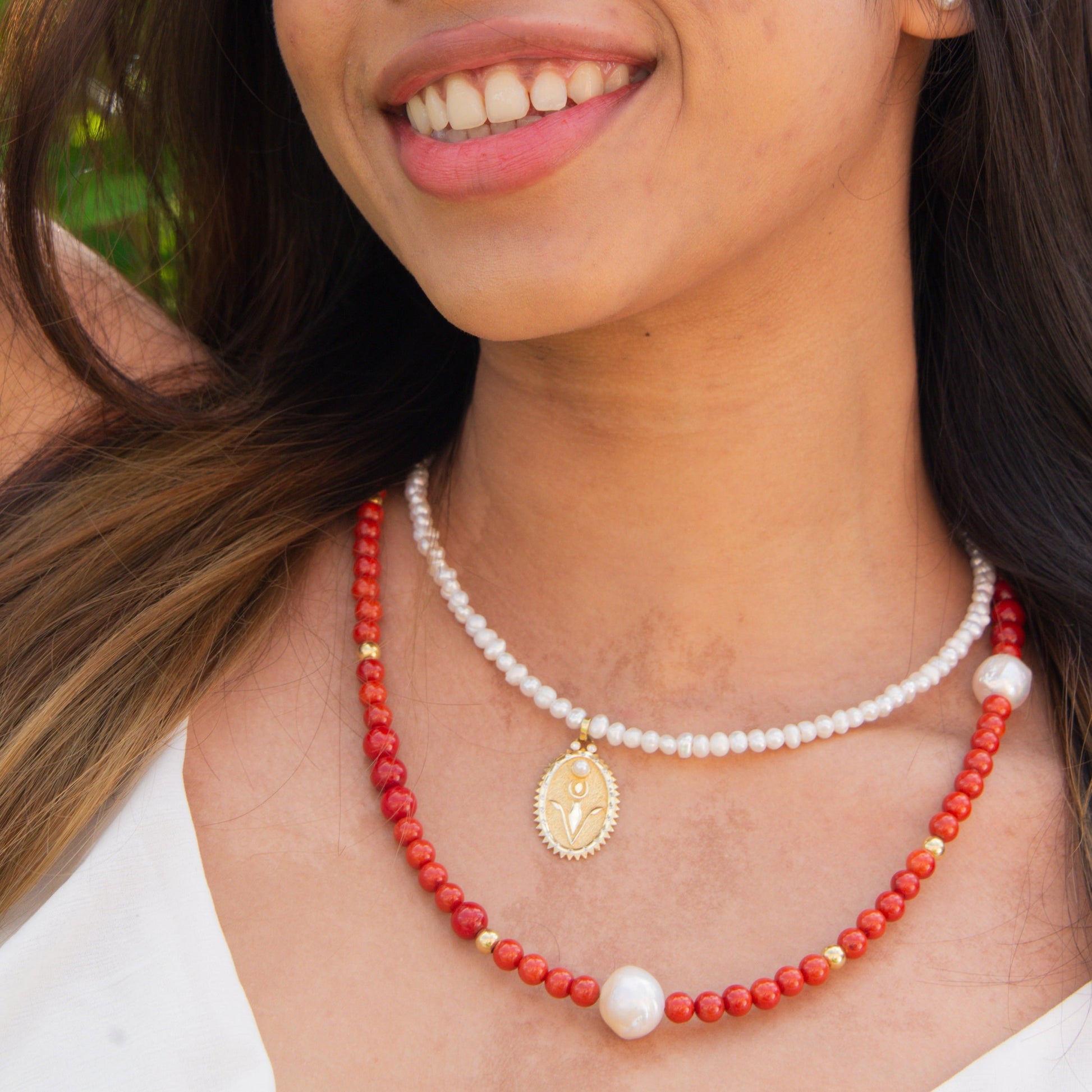 Woman wearing a Pearl Necklace with Rebirth Symbol Plate Pendant