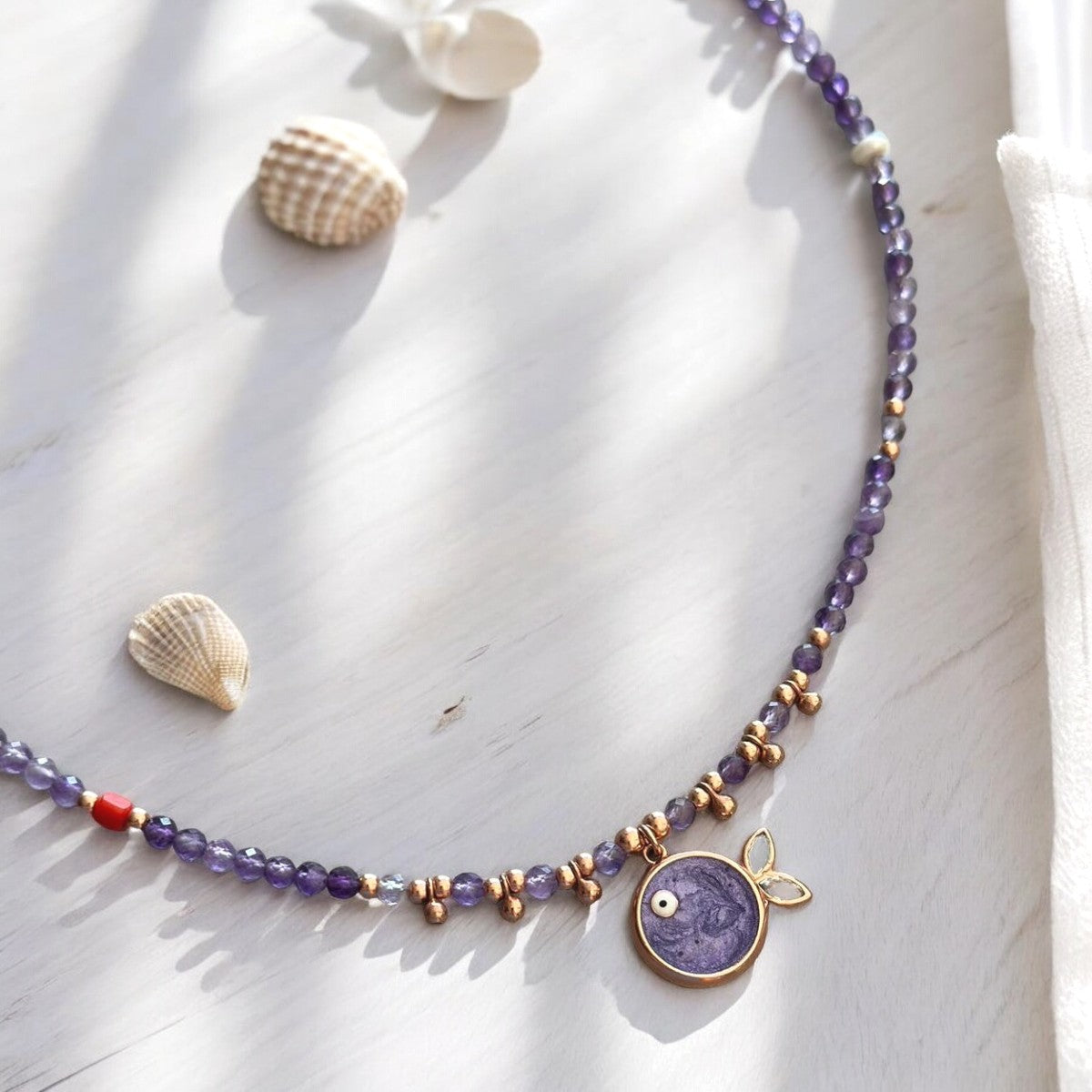 Phuket Amethyst Fish Pendant Necklace in rose gold plated sterling silver, displayed elegantly on a white surface with seashells.