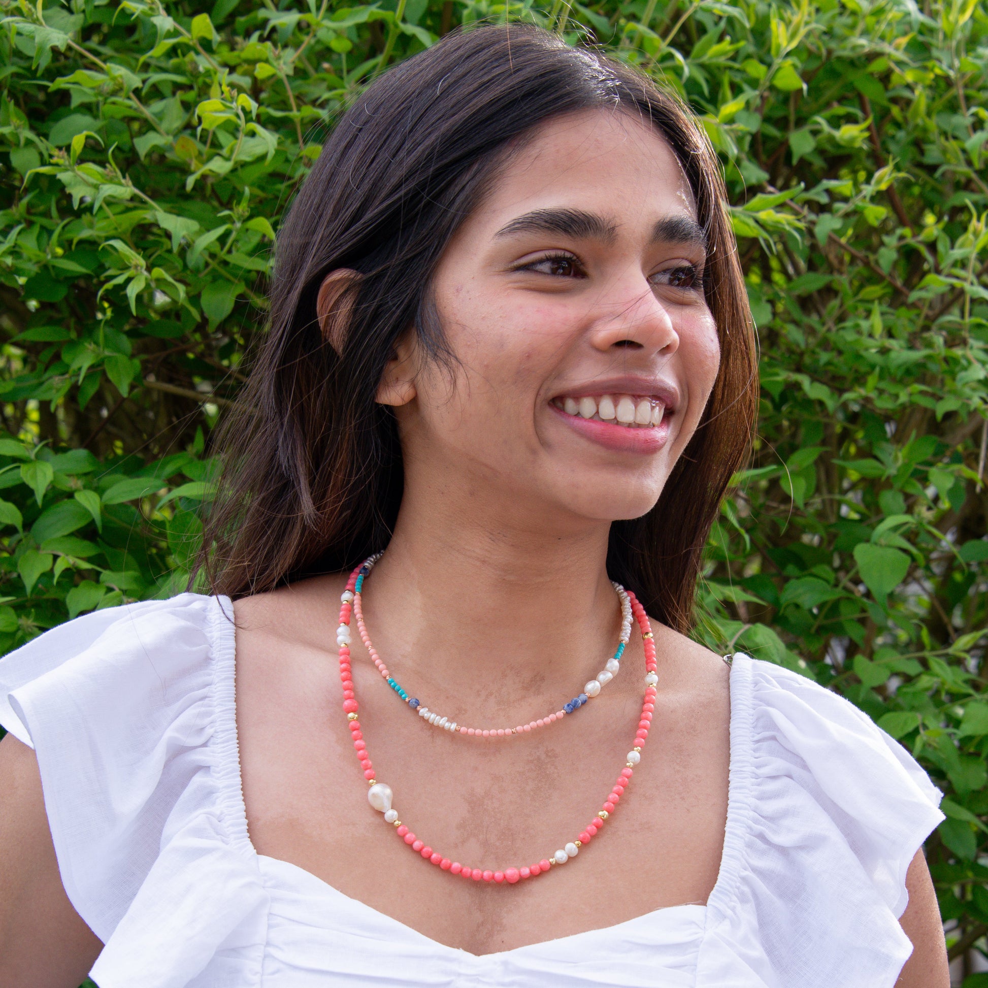 Woman wearing Pink Coral Gemstone Necklace with Baroque Freshwater Pearls outdoors