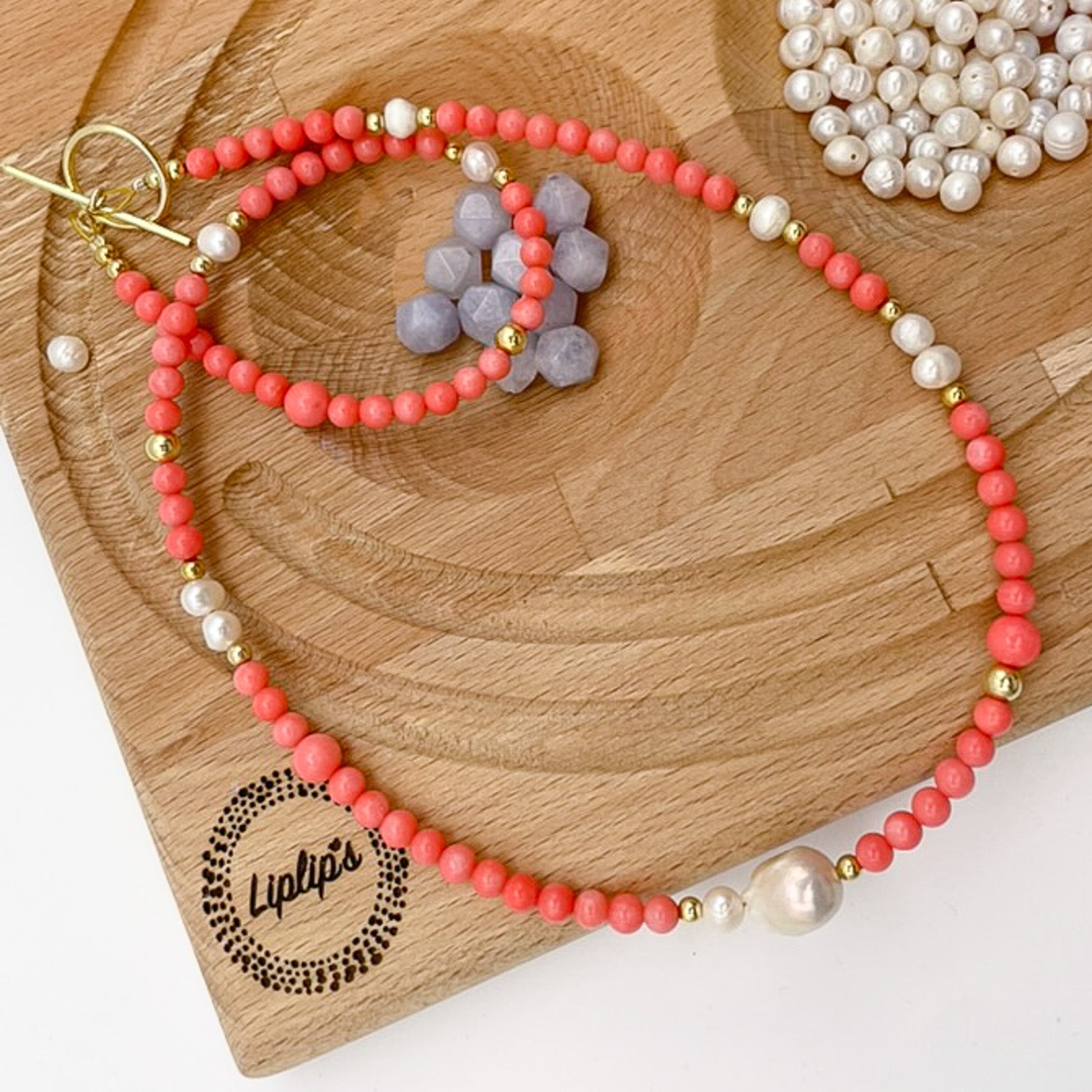 Pink Coral Gemstone Necklace with Baroque Freshwater Pearls displayed on a wooden surface