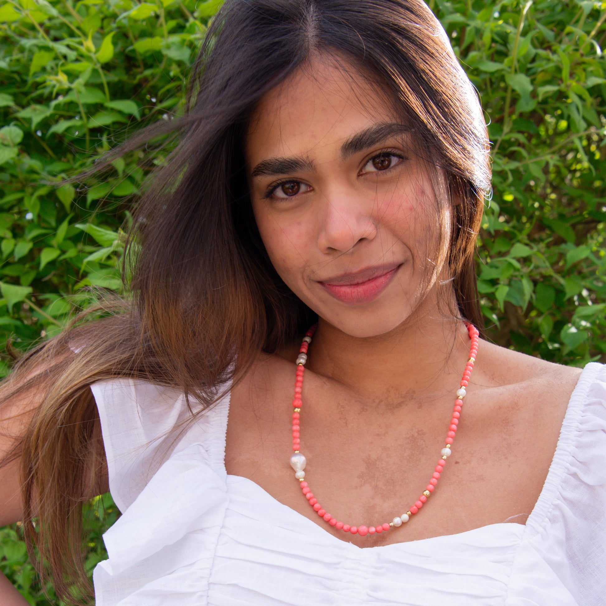 Woman wearing a Pink Coral Gemstone Necklace with Baroque Freshwater Pearls