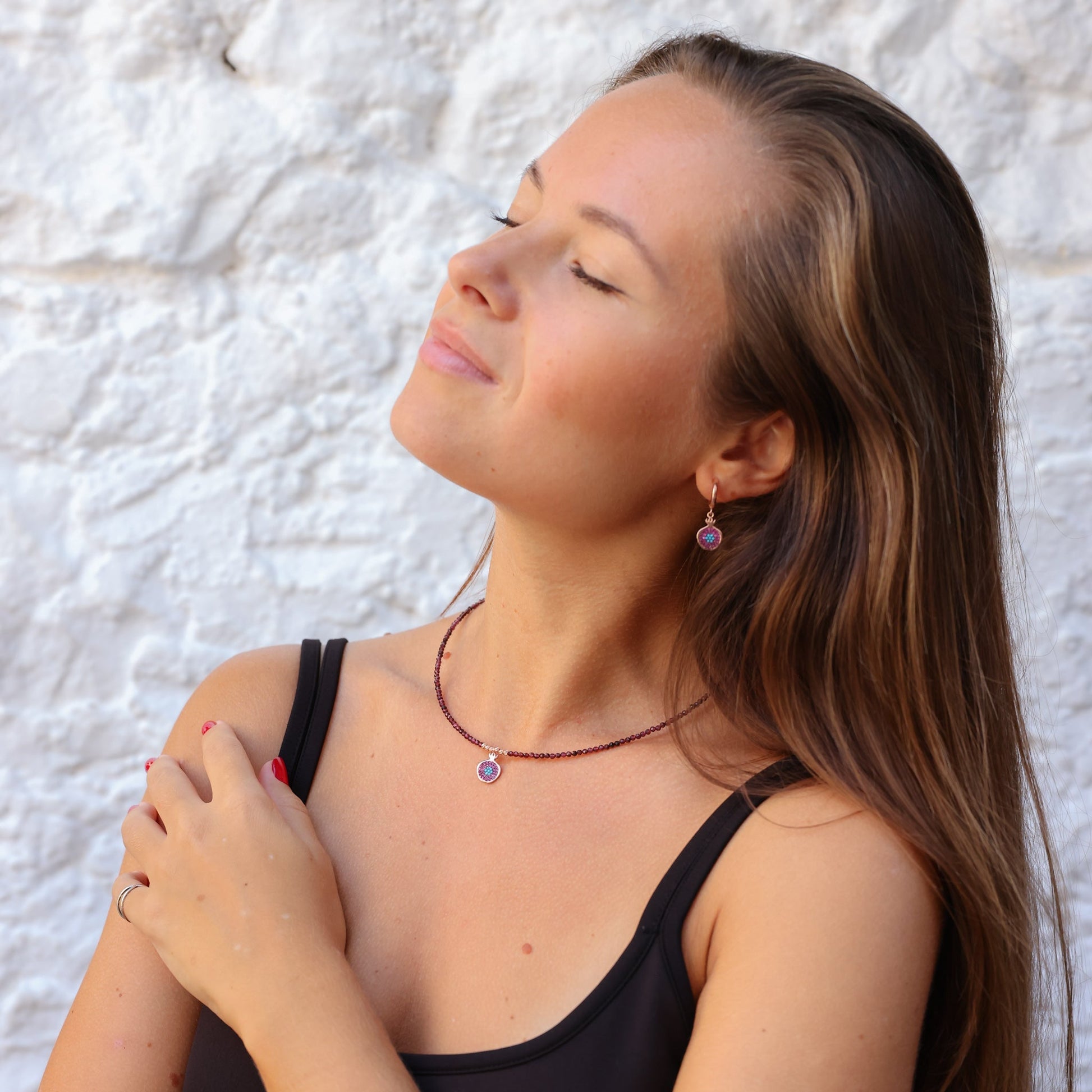 Woman wearing elegant Pomegranate Garnet Earrings and matching necklace against a white background.