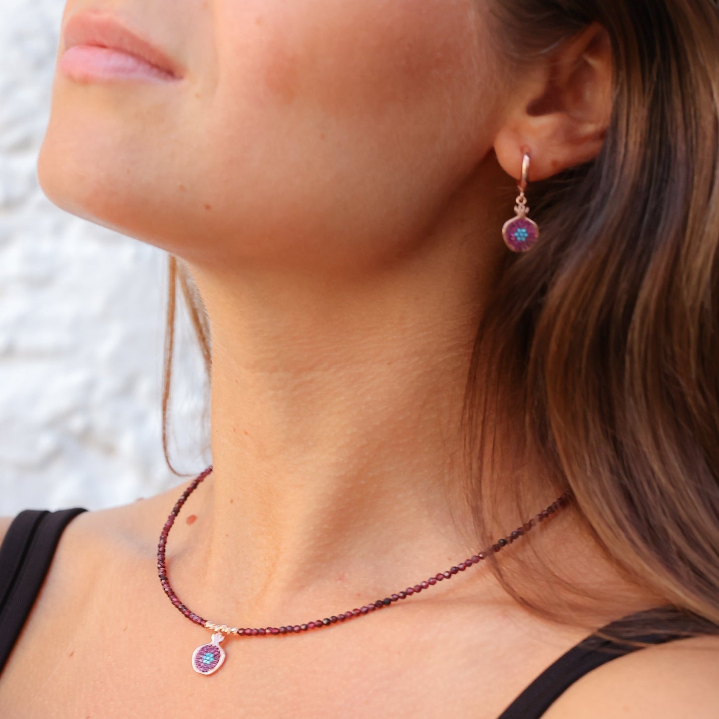 Close-up of woman wearing Pomegranate Garnet Earrings and matching necklace.