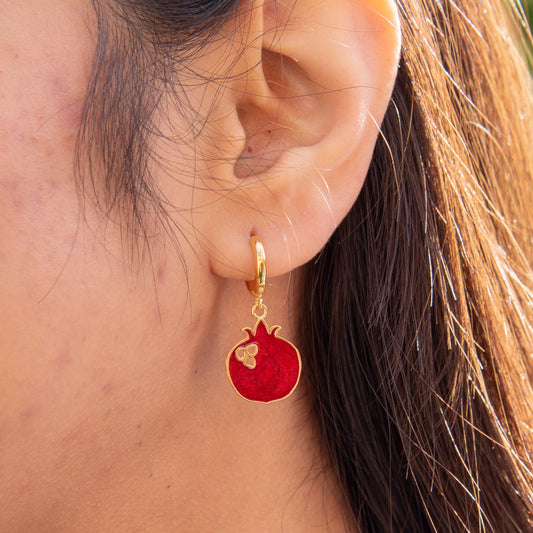 Close-up of Pomegranate Gold Plated Silver Dangle Hoop Earrings worn on a person’s ear.