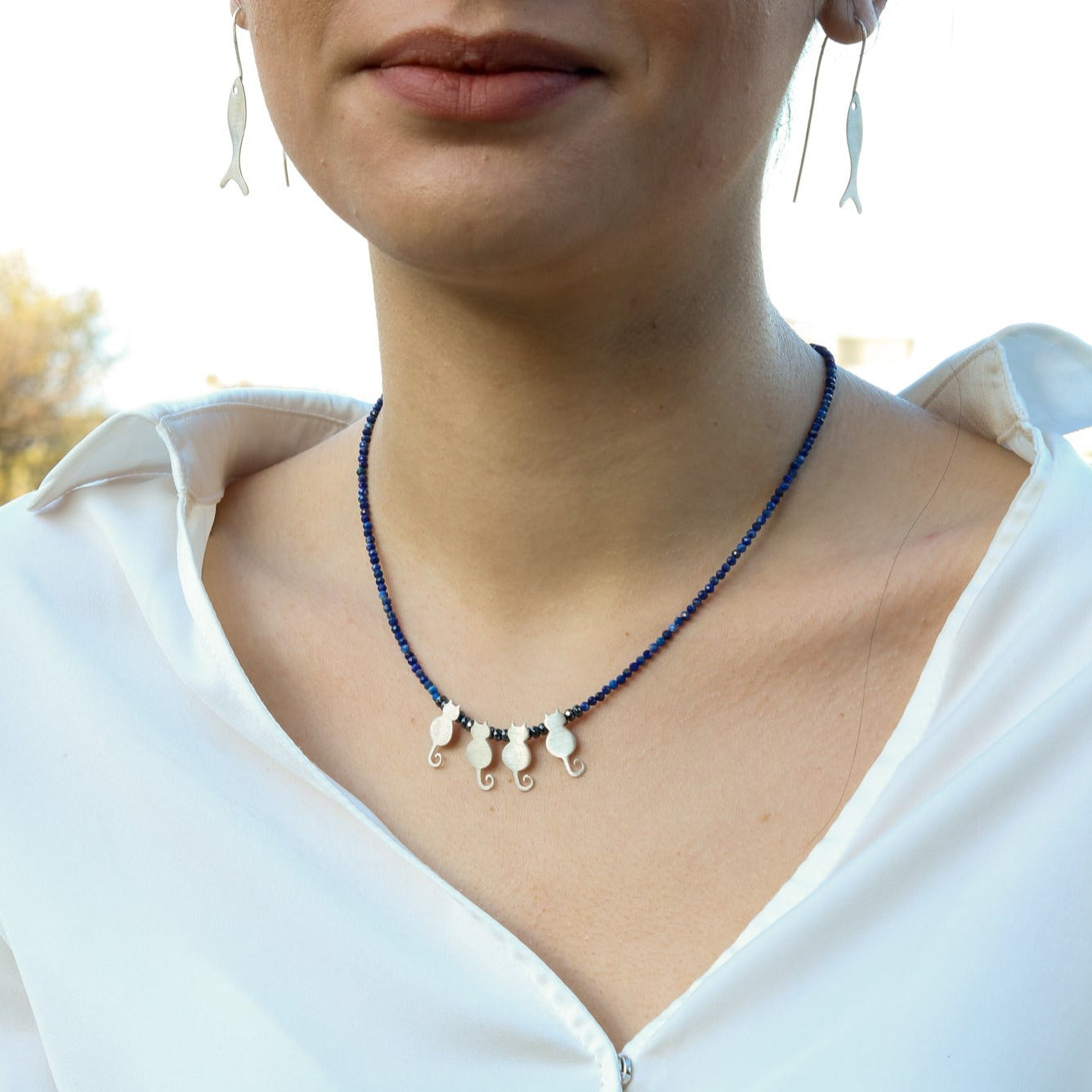 Model wearing Quartet Cats Lapis Silver Necklace with blue beads and four silver cat charmed pendants.