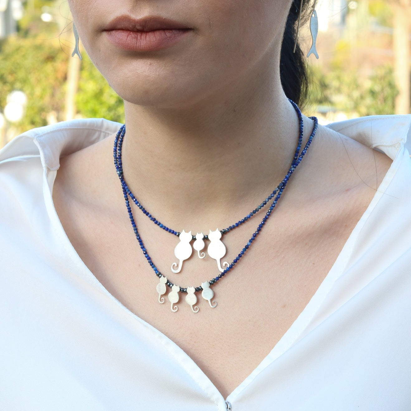 Close-up of woman wearing a Quartet Cats Lapis Silver Necklace with blue beads and cat charms.