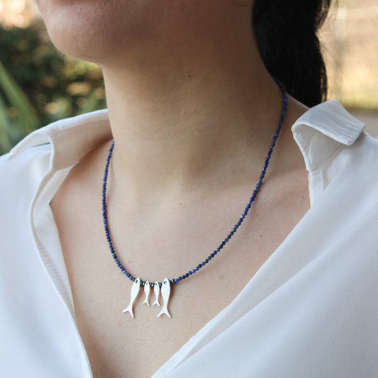 Quartet Fish Family Lapis Necklace worn by a person in a white shirt