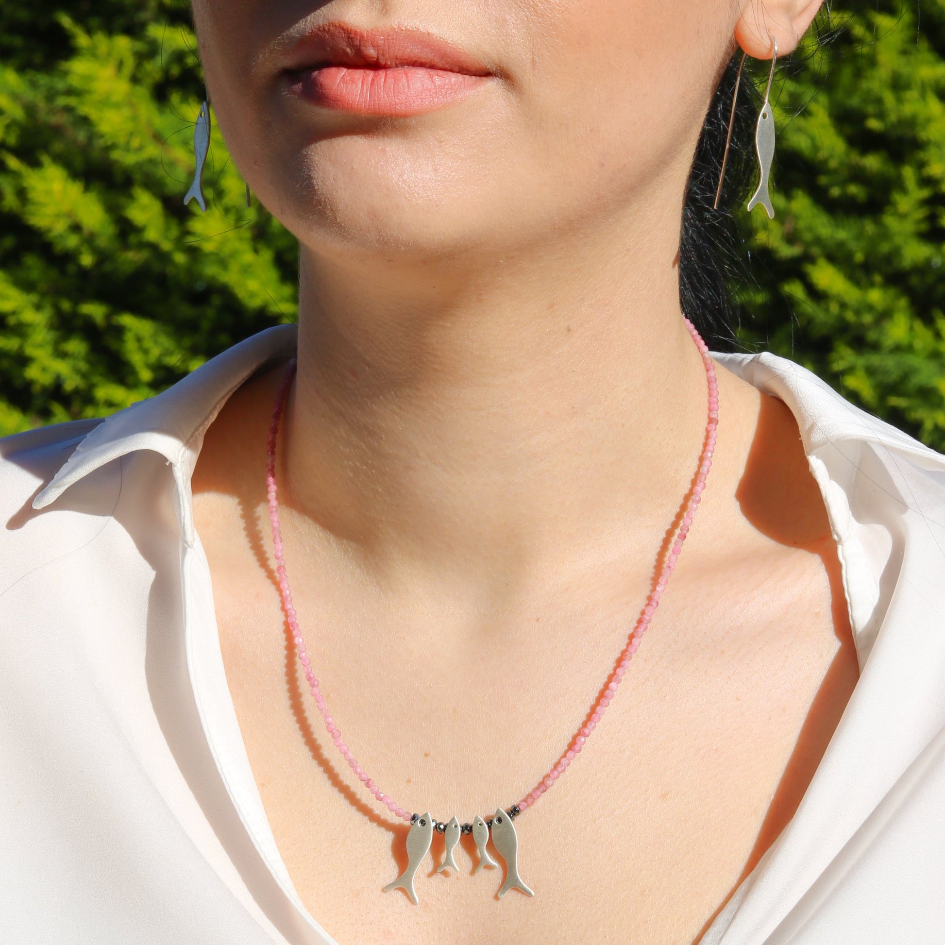 Woman wearing Quartet Fish Family Pink Tourmaline Necklace and matching fish earrings.