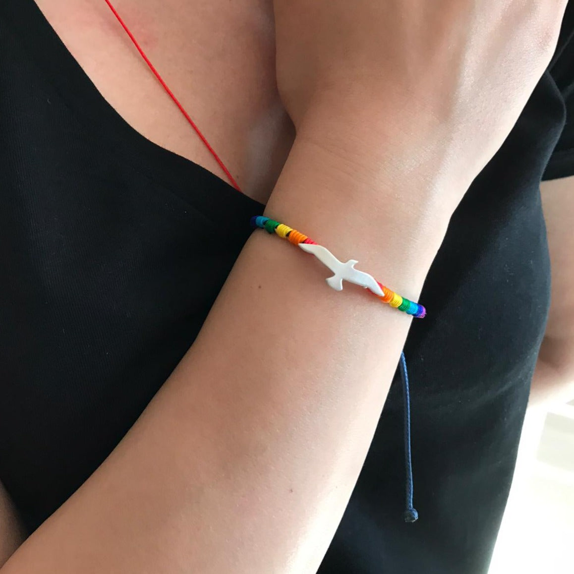 Close-up of a Rainbow Seagull Silver Bracelet on a woman's wrist, featuring a silver seagull pendant and colorful rainbow beads.