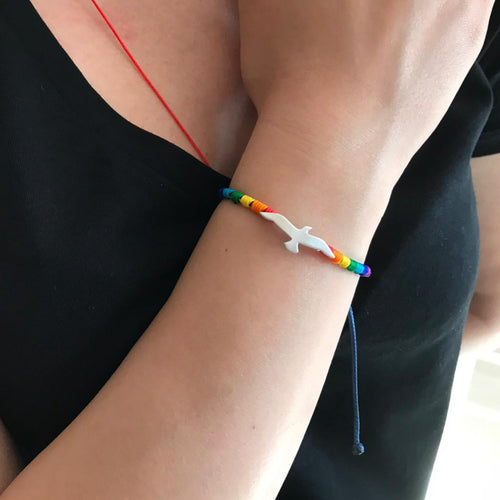 Close-up of a Rainbow Seagull Silver Bracelet on a woman's wrist, featuring a silver seagull pendant and colorful rainbow beads.