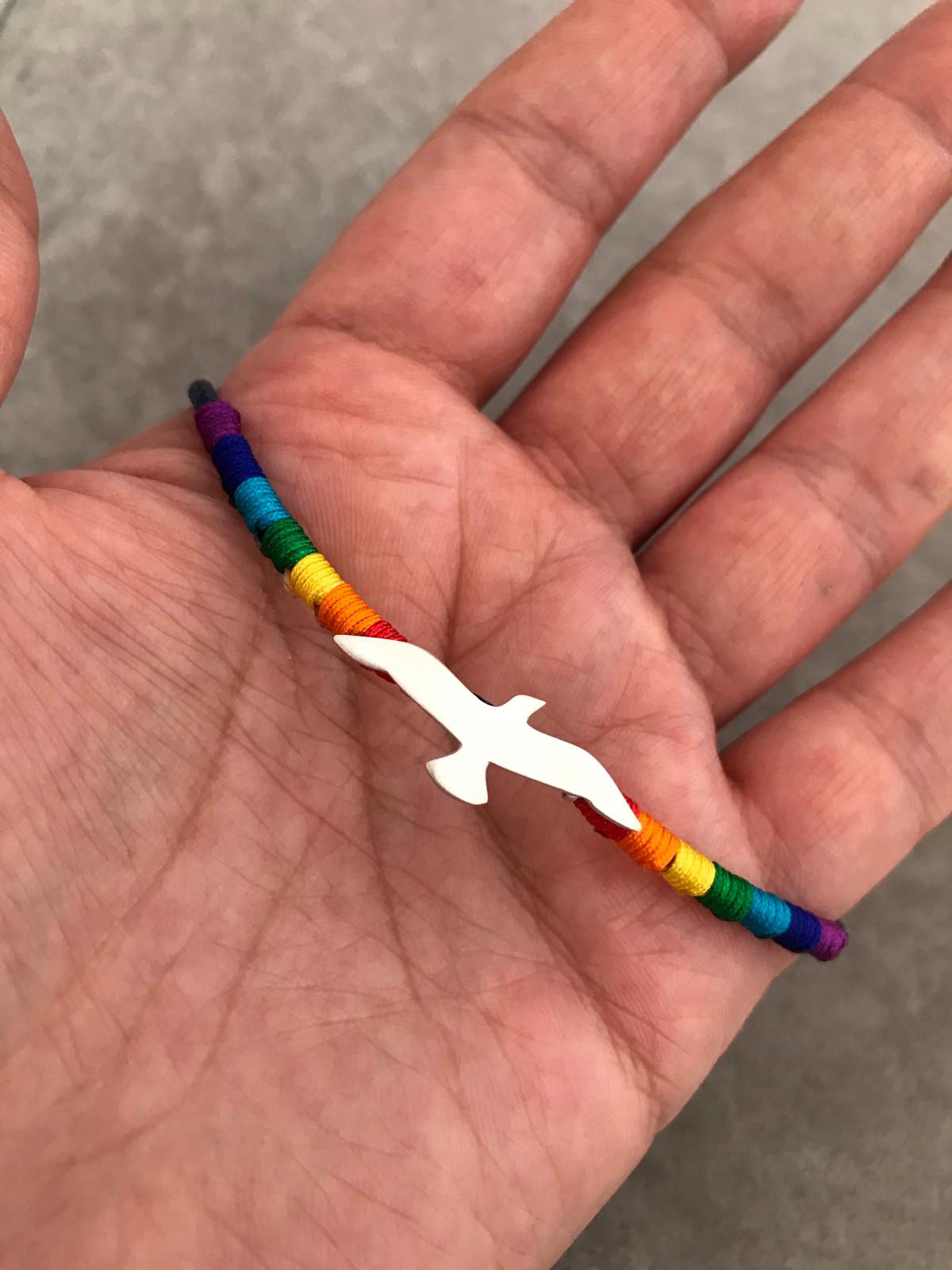 Hand holding Rainbow Seagull Silver Bracelet with colorful thread