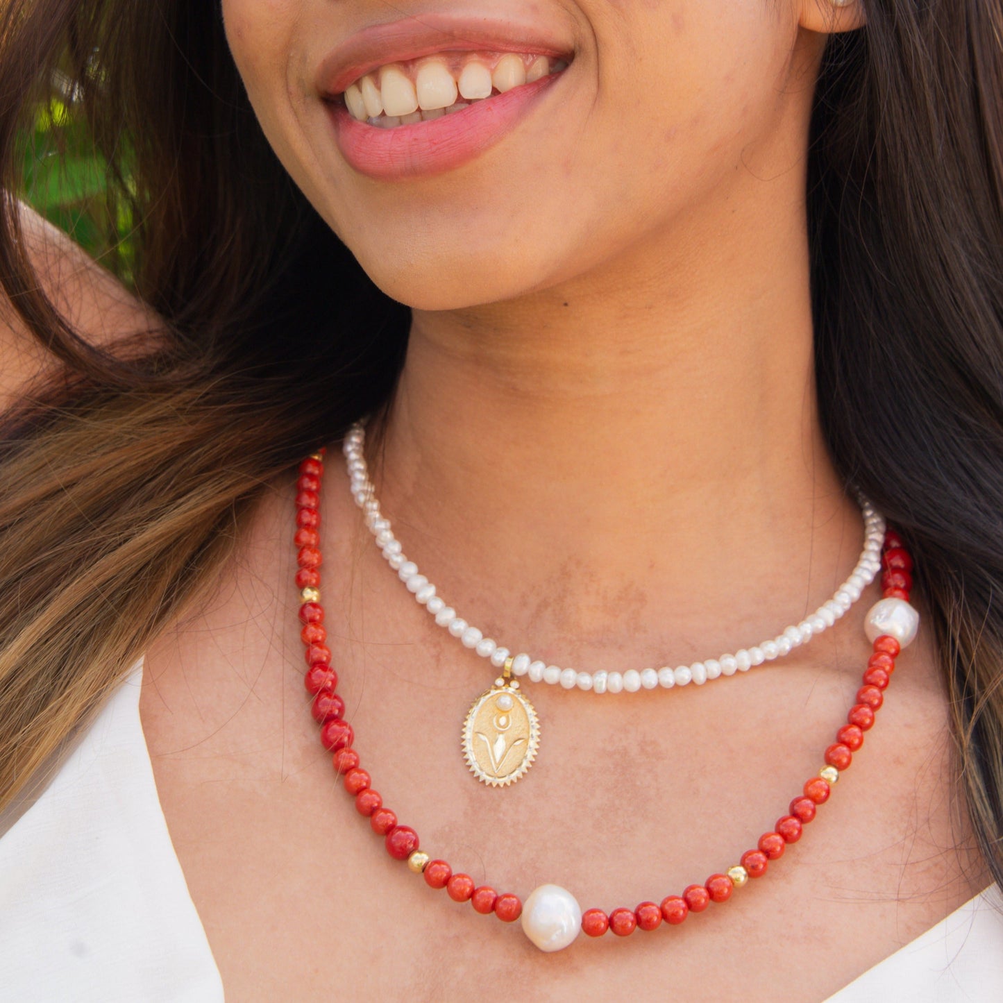 Red Coral Gemstone Necklace with Baroque Freshwater Pearls on a woman with white dress, smiling.