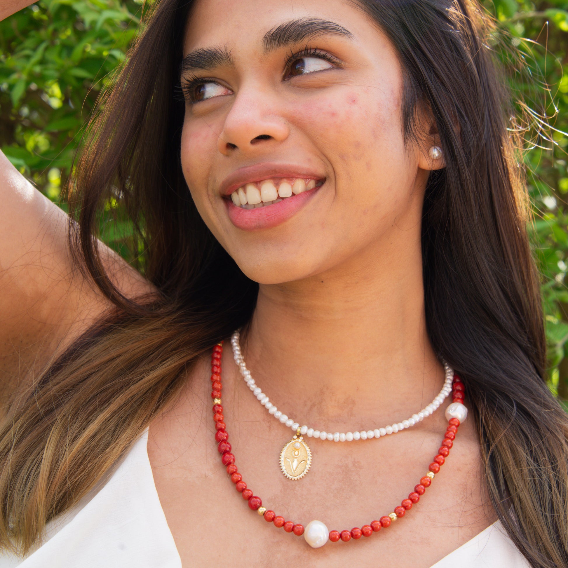 Woman wearing a Red Coral Gemstone Necklace with Baroque Freshwater Pearls and a delicate gold pendant