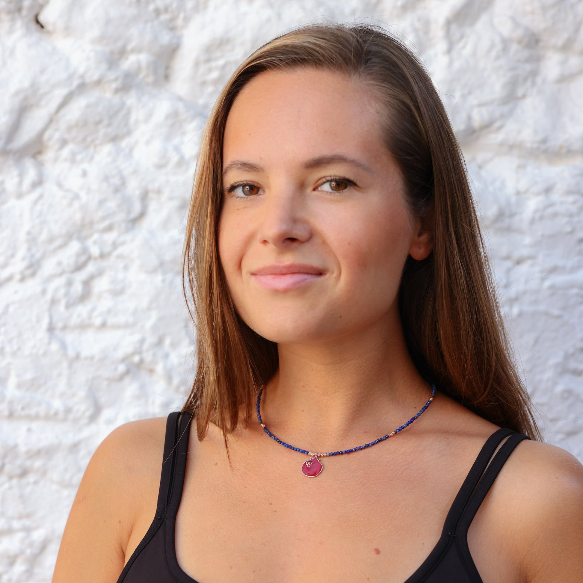 Woman wearing Red Pomegranate Lapis Necklace with blue beads and red pendant