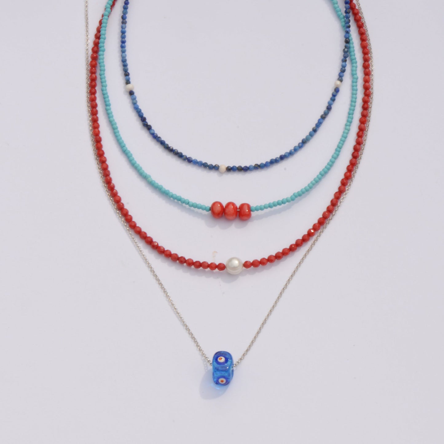 Reds and Blues Gemstone and Silver Necklace Set with various beads in turquoise, navy, and coral colors arranged elegantly.