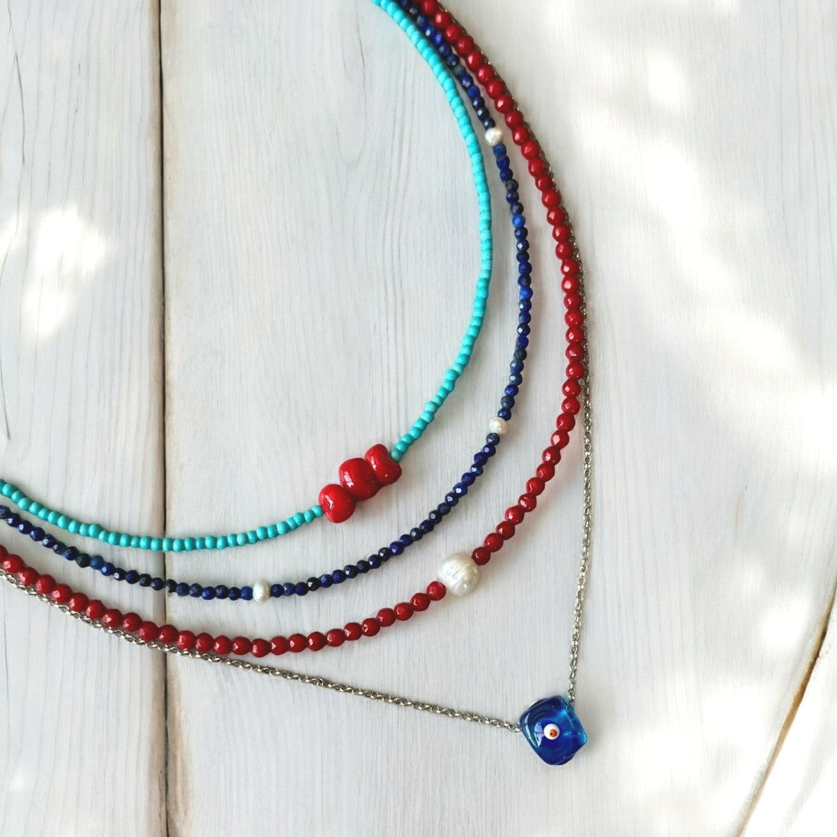 Reds and Blues Gemstone and Silver Necklace Set with multicolored beads on wooden surface